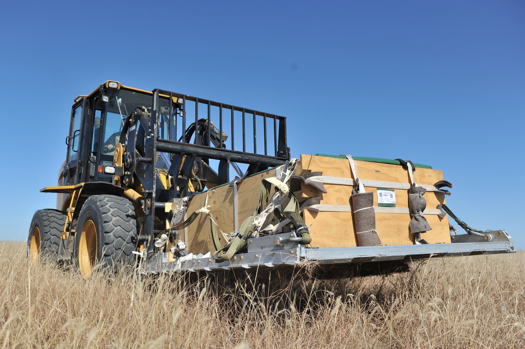 HOLLIS, Okla. – An Airman from the 97th Logistics Readiness Squadron air delivery flight picks up a cargo pallet after it was used for an airdrop training mission Oct. 30, 2014. The training pallets weigh approximately 3,500 pounds and are used by the 58th Airlift Squadron to train loadmasters in the skills they need to perform contingency and humanitarian operations across the world. (U.S. Air Force Photo by Senior Airman Dillon Davis/Released)