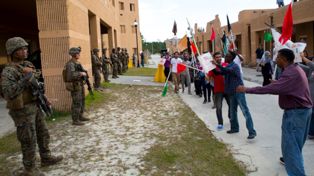 Marines with Echo Company, 2nd Battalion, 8th Marine Regiment, 2nd Marine Division stand guard outside of a simulated embassy while role players protest at a Military Operations on Urban Terrain town aboard Marine Corps Base Camp Lejeune, N.C., Oct. 30, 2014. The Marines provided security for the embassy as part of an embassy reinforcement operation in conjunction with Exercise Bold Alligator 2014. Bold Alligator is a scenario-driven, simulation-supported, amphibious assault exercise and is the largest exercise held on the East Coast. The exercise is scheduled to be conducted through Nov. 10. The battalion is participating in the exercise to prepare for the unit’s upcoming deployment as the ground combat element for the Black Sea Rotational Force.