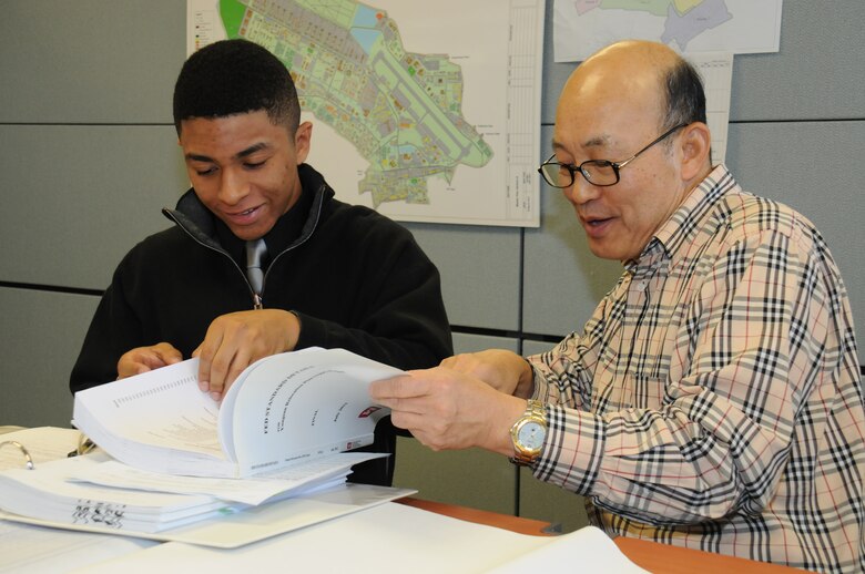 Seoul American High School senior Warren Nieto (left) learns about mechanical engineer design drawings from Eugene Min, chief of the tech review section at the district compound Nov. 5.