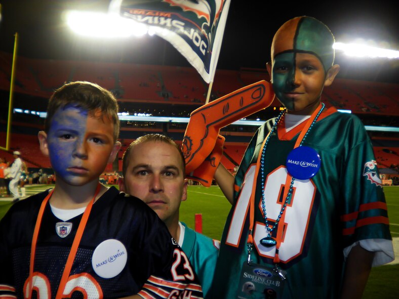 Senior Master Sgt. Jason Cooper, 5th Reconnaissance Squadron aircraft maintenance squadron superintendent, stands with his sons Baily, left, and Dillon on the Miami Dolphins stadium field before the game Nov. 18, 2010, Miami, Fla. The Cooper family received sideline passes for the game and met the players after the game. (Courtesy photo)