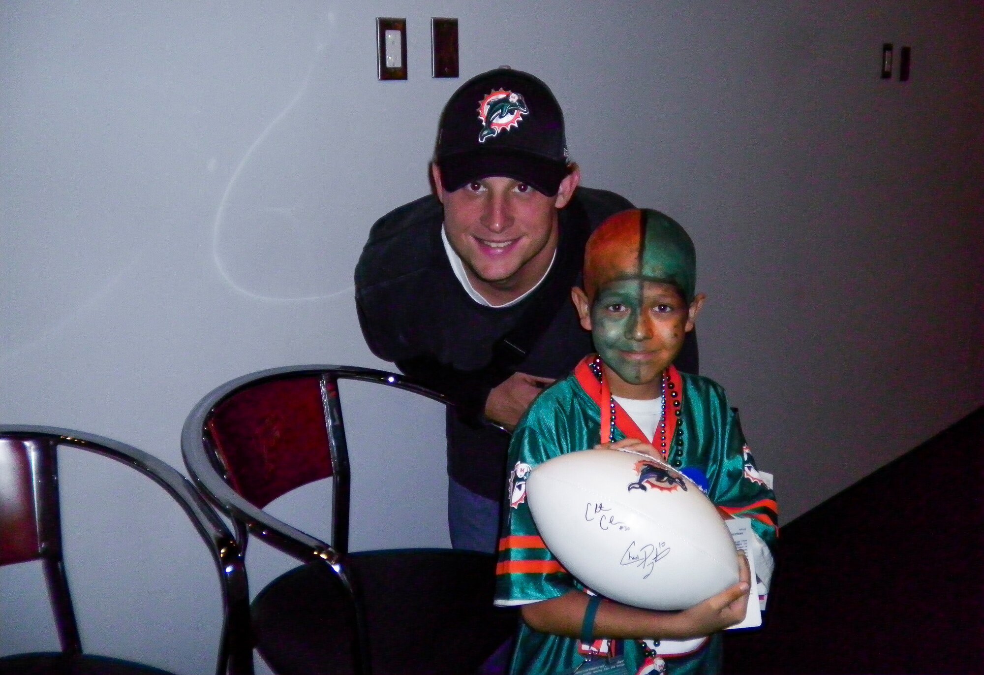 Dillon Cooper, son of Senior Master Sgt. Jason Cooper, 5th Reconnaissance Squadron aircraft maintenance squadron superintendent, receives a signed football from Chad Pennington, Miami Dolphins quarterback, in the Miami Dolphins stadium Nov. 18, 2010, Miami, Fla. “It felt great knowing that I was able to choose whatever I wanted to do,” Dillon said. “It was amazing to be able watch the Dolphins game live, and to meet and interact with the players.” (Courtesy photo)