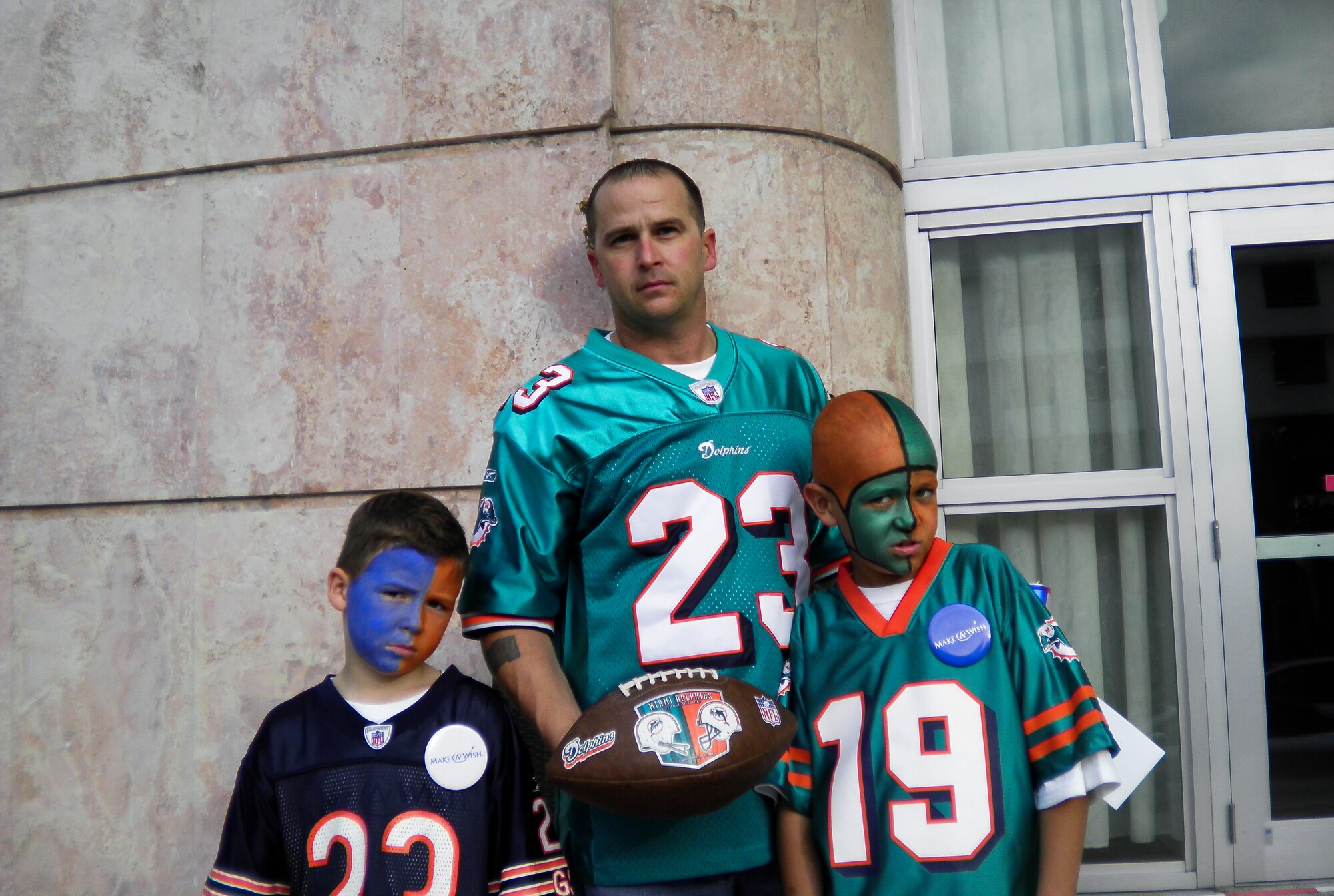 Senior Master Sgt. Jason Cooper, 5th Reconnaissance Squadron aircraft maintenance squadron superintendent, stands with his sons Baily, left, and Dillon outside the Miami Dolphins stadium before the game Nov. 18, 2010, Miami, Fla. The Cooper family received sideline passes for the game and met the players after the game. (Courtesy photo)