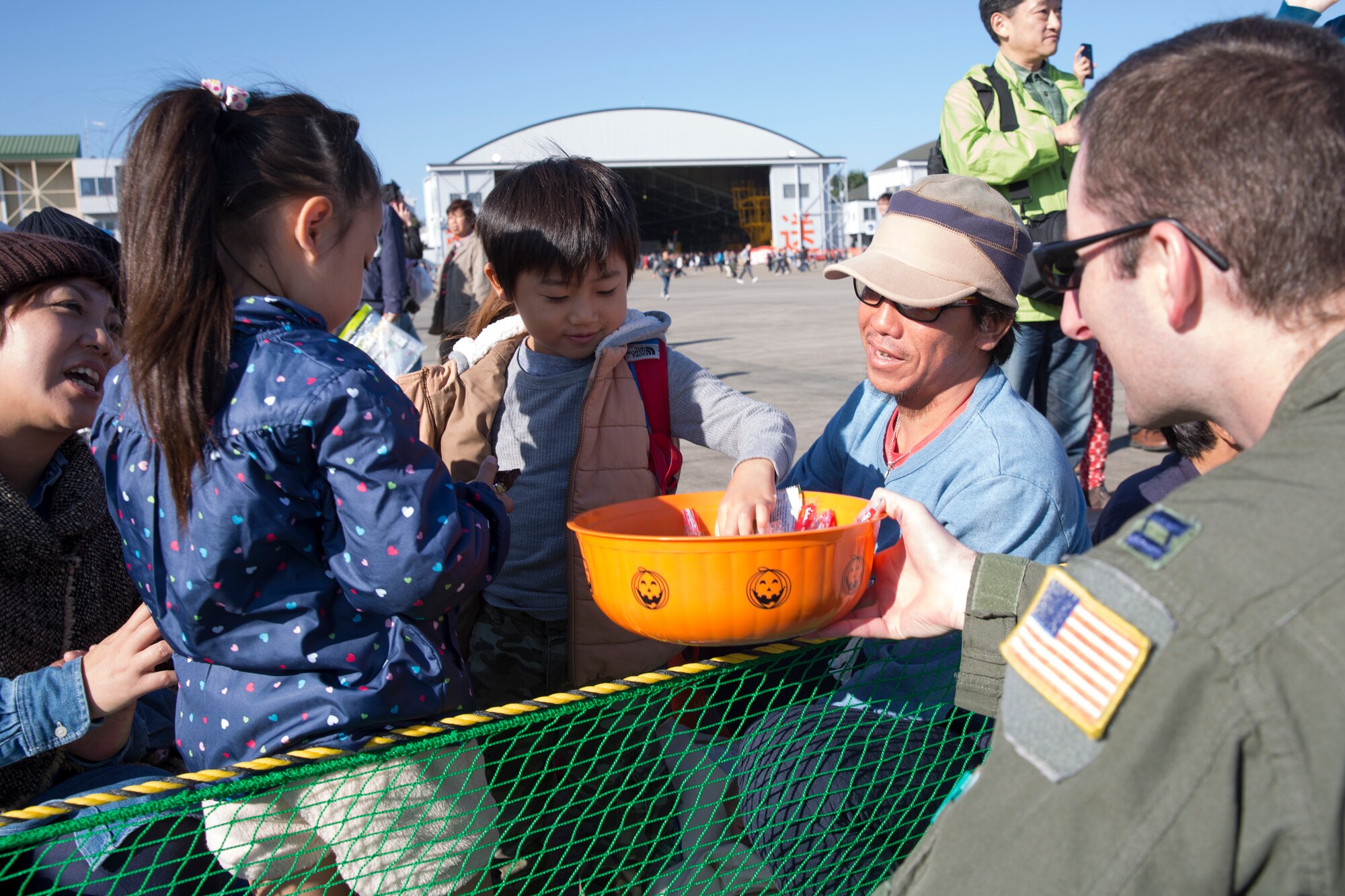 U.S. Air Force Capt. Doug Lincoln, 459th Airlift Squadron UH-1N pilot, offers candy to a visitor during an airshow at Iruma Air Base, Japan, Nov. 3, 2014. Airmen from the 459 AS participated in the annual Iruma Air Show. (U.S. Air Force photo by Osakabe Yasuo/Released) 