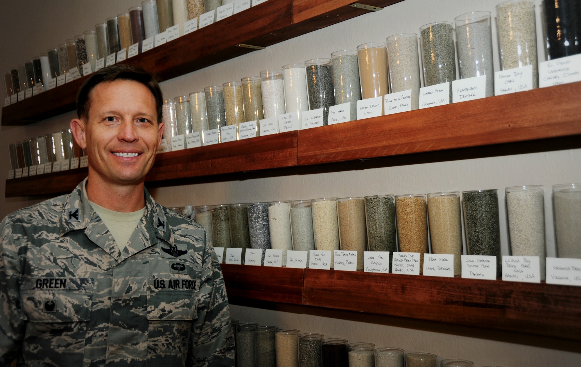Col. Gregory Green, 375th Air Mobility Wing Vice Commander, stands in front of his personal collection of 315 jars of sand he has acquired over his 22 year Air Force career.  He houses his collection on custom made shelves with labels describing where the sand is from. (U.S. Air Force photo/Karen Petitt)