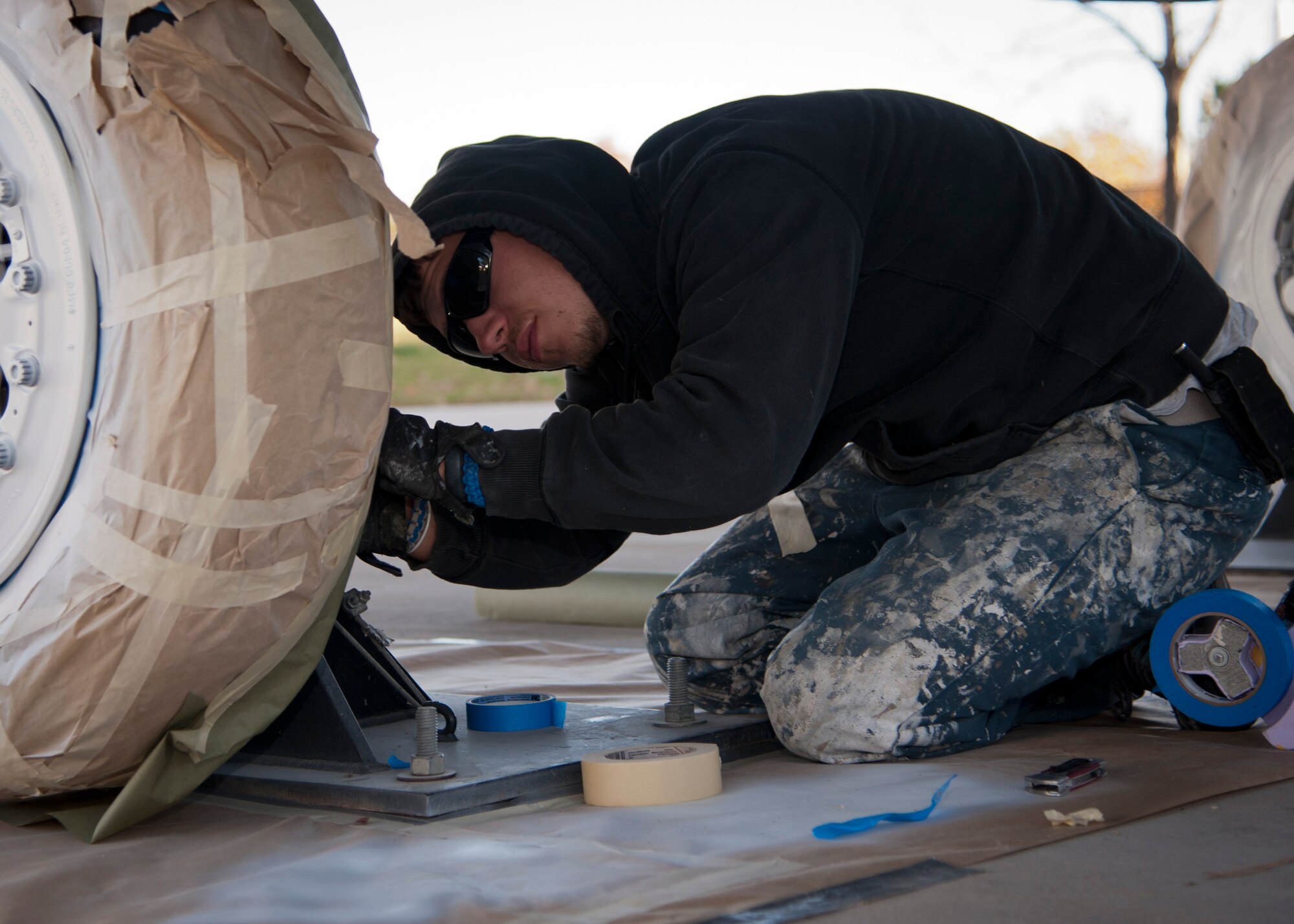 PETERSON AIR FORCE BASE, Colo. – Frank Fuentes, a painting contractor, wraps the wheel of an F-15 Strike Eagle aircraft with paper and tape in preparation for paint at the base museum Oct. 30. Fuentes is part of a contracted crew hired to repaint and touch up 10 aircraft maintained by the museum to ensure these artifacts remain accurate representations of these once high-soaring crafts that now reside at Peterson AFB. (U.S. Air Force photo/Staff Sgt. J. Aaron Breeden)