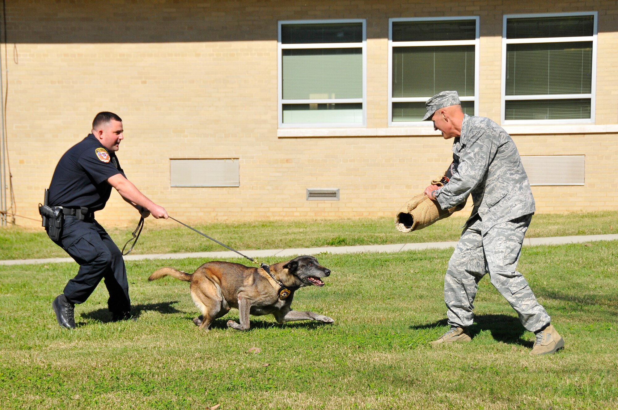 Police Officer Jason Layne (left) instructs Arnold Police K-9 Officer Bikkel in an attack demonstration during Bikkel’s retirement celebration on Oct. 21. Col. James Krajewski, the Arnold Engineering Development Complex (AEDC) Test Support Division director, acts as the antagonist for the demonstration. (Photo by Rick Goodfriend)