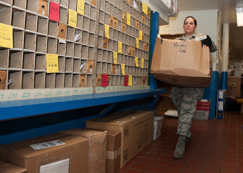 Senior Airman Natalie George, 8th Communications Squadron postal specialist, carries a package at the post office at Kunsan Air Base, Republic of Korea. From Nov. 24 to Jan. 3, the Kunsan post office will extend their hours from 7 a.m. to 6 p.m. to accommodate shift workers, ensuring packages arrive to their destination in time for the holidays. (U.S. Air Force photo by Senior Airman Katrina Heikkinen/Released)
