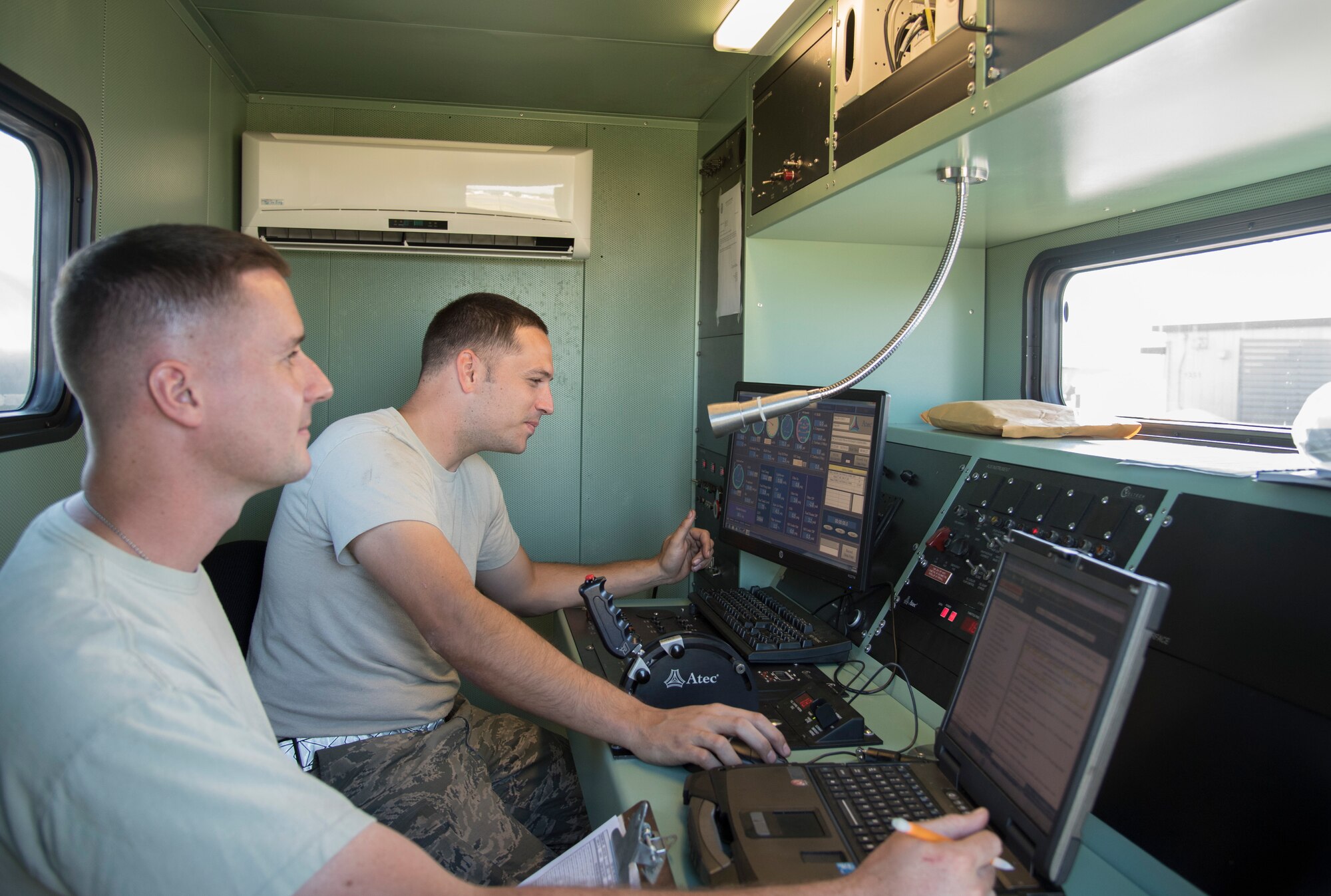 Staff Sgts. Jeffrey Stephens (right) and Devon Loftis (left), both 374th Maintenance Squadron aerospace propulsion flight craftsman, sit in a test cab as they perform a battery of tests on a completed C-130 T56 engine at the 374 MXS Test Cell at Yokota Air Base, Japan, Oct. 29, 2014. From the test cab, the Airmen can diagnose any problem an engine may have and fix it in a short amount of time. (U.S. Air Force photo by Senior Airman Michael Washburn/Released)
