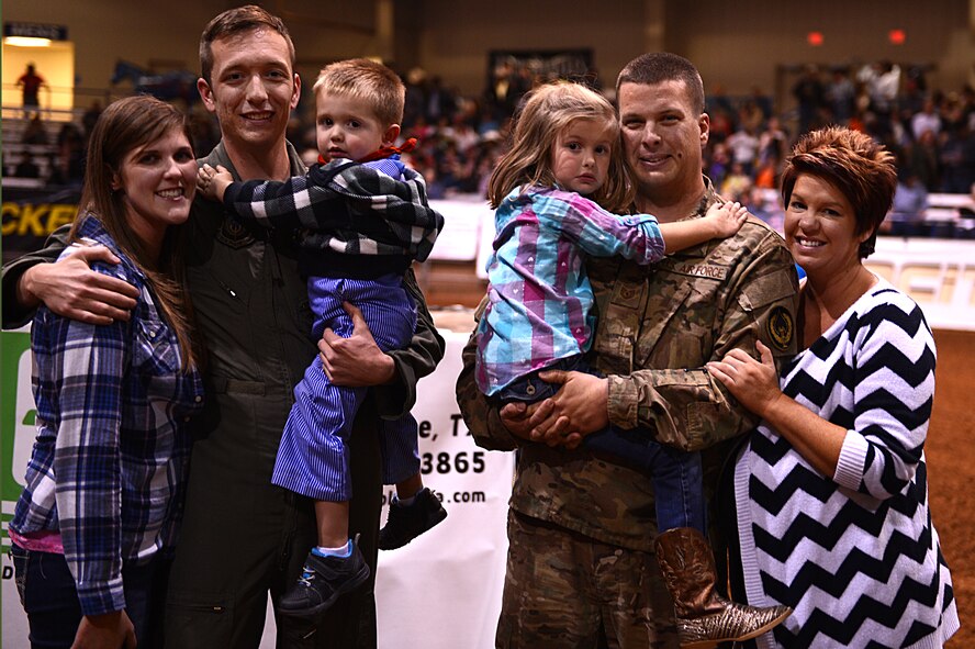 U.S. Air Force Tech. Sgt. Alan McClanahan, 27th Special Operations Aircraft Maintenance Squadron, and Staff Sgt. James Kinsley, 524th Special Operations Squadron, hold their loved ones during L.J. Jenkins invitational at the Curry County Events Center Oct. 31, 2014 in Clovis, N.M. The families were provided a surprise reunion during a military appreciation portion of the event. (U.S. Air Force photo/ Staff Sgt. Matthew Plew)