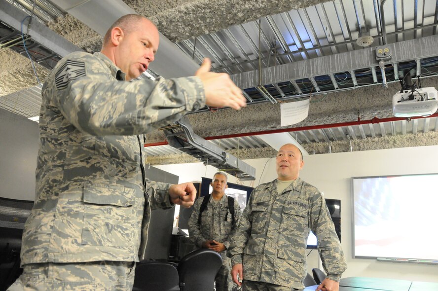 U.S. Air Force Chief Master Sgt. James W. Hotaling, command chief master sgt. of the Air National Guard, accepts a coin from Chief Master Sgt. Reid T. Tsubota, Commander of the Hawaii Air National Guard Eagle Vision unit, during his visit to the 154th Wing at Joint Base Pearl Harbor Hickam on Nov. 5, 2014. Hotaling describes the collection of commander's coins he keeps in his office and how he randomly pulls a coin and describes the memory associated when he received it.  (U.S. Air Force photo by Airman 1st Class Robert Cabuco)