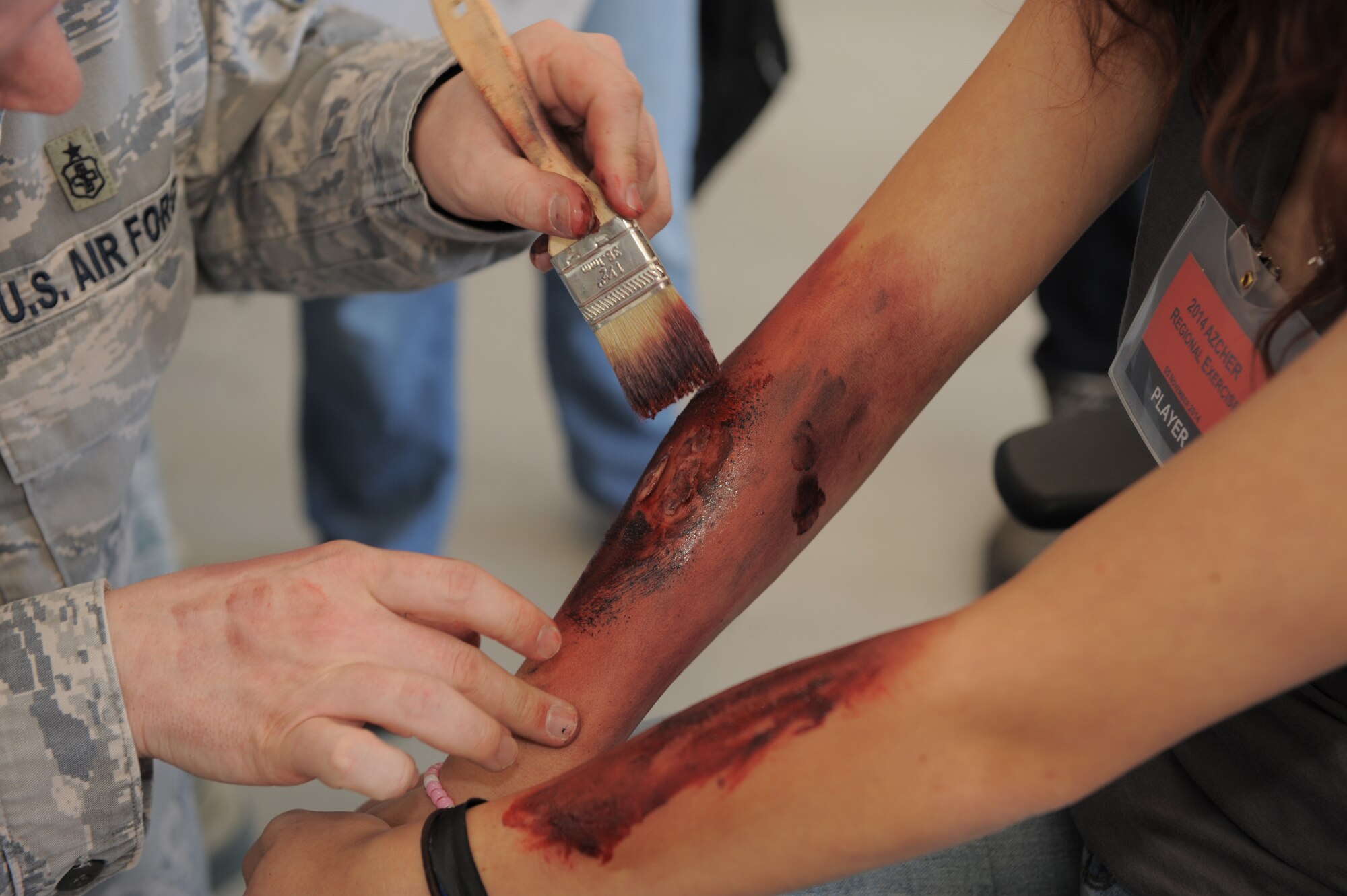 U.S. Air Force Tech. Sgt. Daniel Nored, 355th Aerospace Medicine Squadron flight and operational medical clinic NCO in charge, applies makeup to a simulated victim during a Natural Disaster Medical System exercise at Davis-Monthan Air Force Base, Ariz., Nov. 5, 2014. NDMS exercises allow D-M to partner with the surrounding medical community and train on full-scale medical evacuations while improving readiness. (U.S. Air Force photo by Airman 1st Class Chris Drzazgowski/Released)