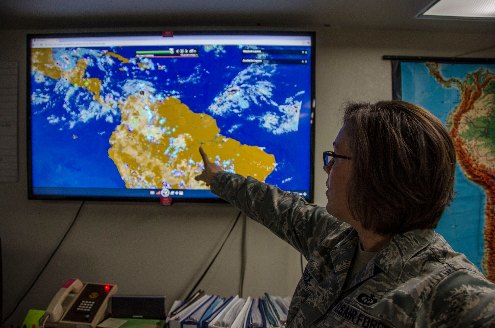 Staff Sgt. Toni Pierce, 612th Support Squadron Weather Forecaster, points to areas in South America that have the possibility of thunder storms at Davis-Monthan AFB, Ariz., Oct. 20, 2014. Members of the weather flight also issues weather watches, warnings and advisories protecting personnel and assets across a 15.6 million square mile radius. (U.S. Air Force photo by Staff Sgt. Adam Grant/Released) 