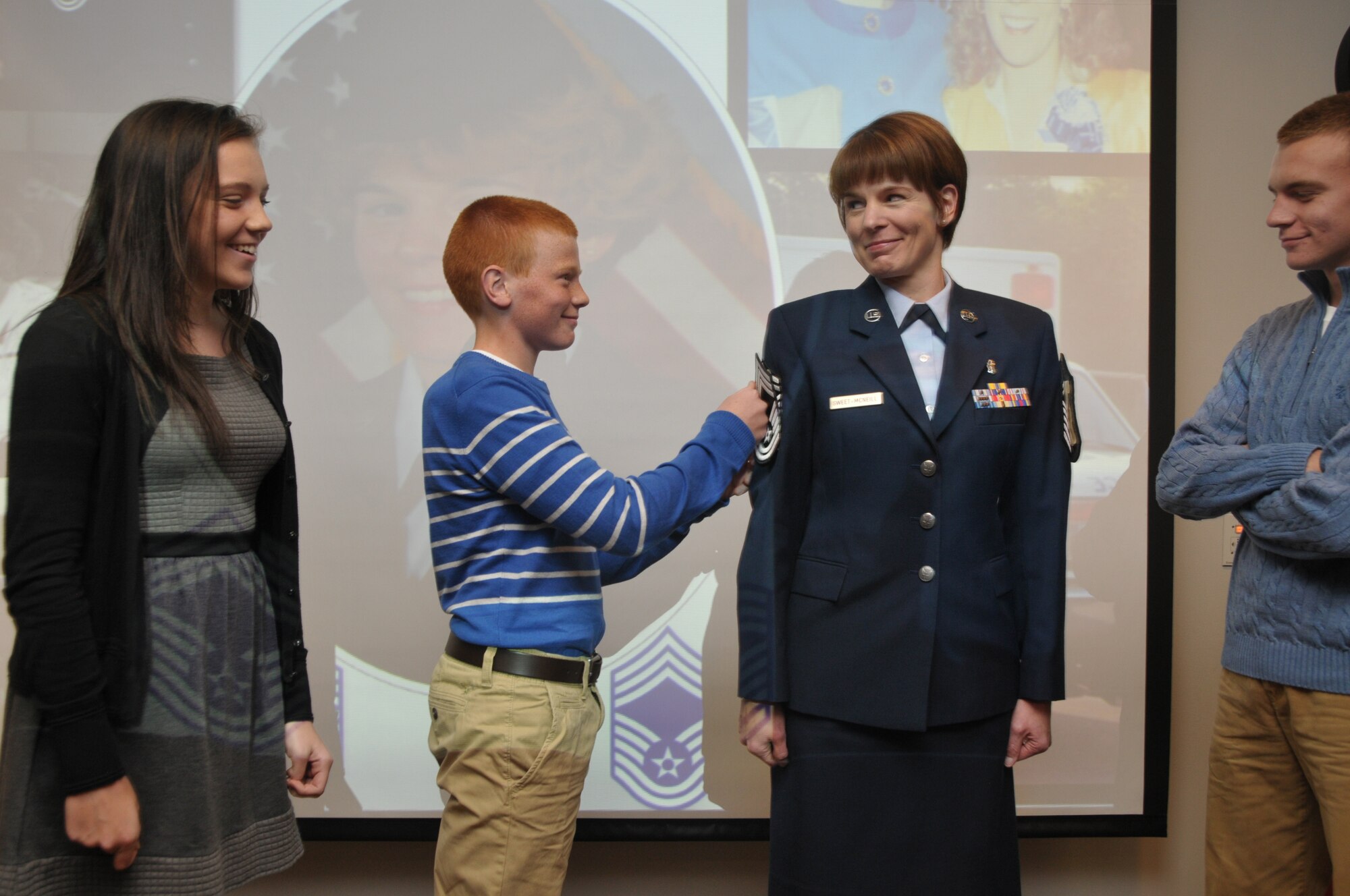 Newly promoted Chief Master Sgt. Jacqueline Sweet-McNeill gets pinned by her son, Nolan, as daughter, Olivia, and eldest son, Ryan, look on during a promotion ceremony at Stratton Air National Guard Base, New York, on Nov. 2, 2014. Sweet-McNeill is the 109th Medical Group superintendent. (U.S. Air National Guard photo by Tech. Sgt. Catharine Schmidt/Released)