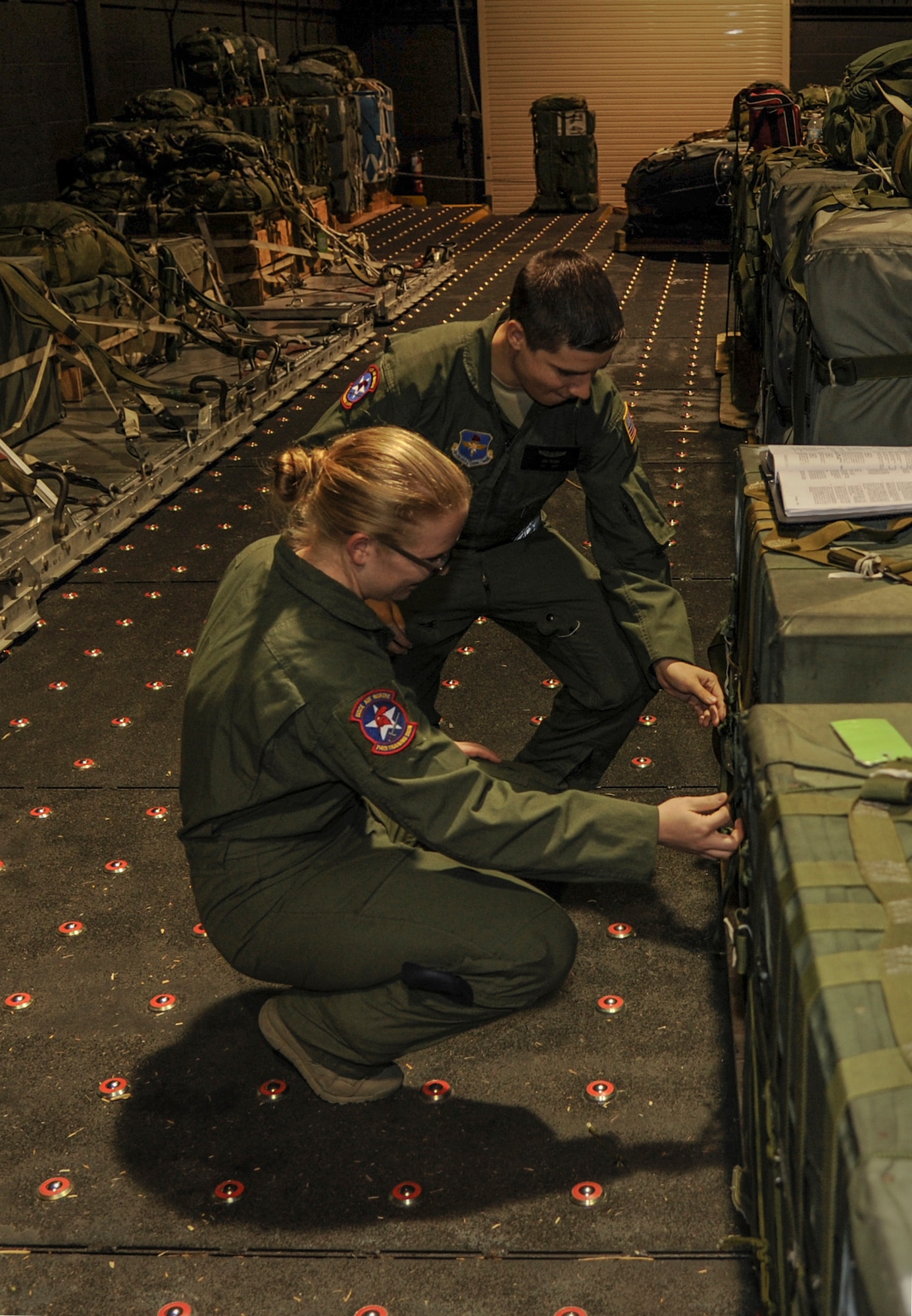 Airman 1st Class Taylor Boeckner and Airman 1st Class Ian Frank, 714th Training Squadron C-130J loadmaster students, practice properly securing cargo Oct. 29, 2014, at Little Rock Air Force Base, Ark. C-130J loadmaster students train as a pair throughout their extensive schooling with the 714th TRS. (U.S. Air Force photo by Airman 1st Class Harry Brexel)