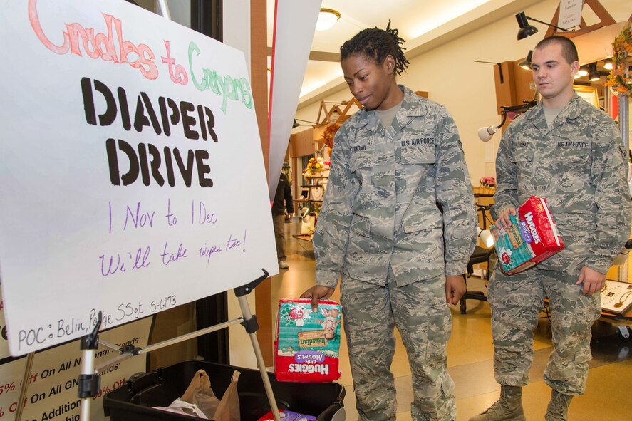 Senior Airman Nehesia Edmond and Airman 1st Class Brian Thomas donate diapers to the Cradle to Crayons diaper drive at Hanscom Air force Base Exchange, which runs through Dec. 1. Cradles to Crayons provides children from birth through age 12 living in homeless or low-income situations with the essential items they need to thrive at home, school and at play. (U.S. Air Force photo by Mark Herlihy)