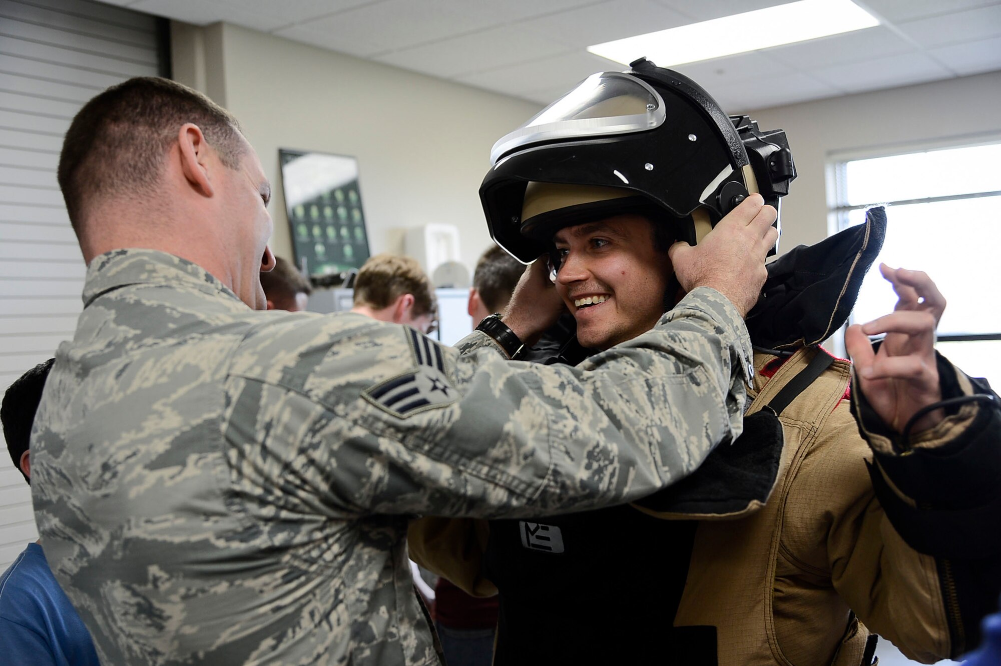 Senior Airman John Barr, 6th Civil Engineer Squadron explosive ordnance disposal technician, fits a helmet onto Sam Bird, chaperon of the United Kingdom tour group, at MacDill Air Force Base, Fla., Nov. 4, 2014. After a short briefing, the group was given the opportunity to try on EOD equipment and go inside a HUMVEE. (U.S. Air Force photo by Airman 1st Class Danielle Conde/Released)