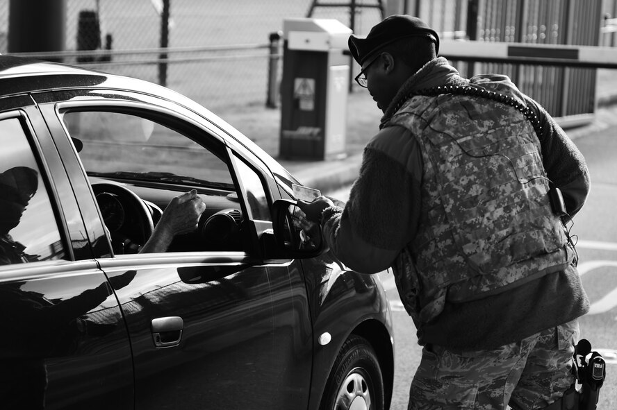 Airman 1st Class Lance Ryans, 422nd Security Forces Squadron patrolman, checks an identification card at the main gate to RAF Croughton, United Kingdom, Nov. 5, 2014. Ryans makes it a point to politely greet individuals who access the installation and set a positive tone for their visit. (U.S. Air Force photo by Staff Sgt. Jarad A. Denton/Released)