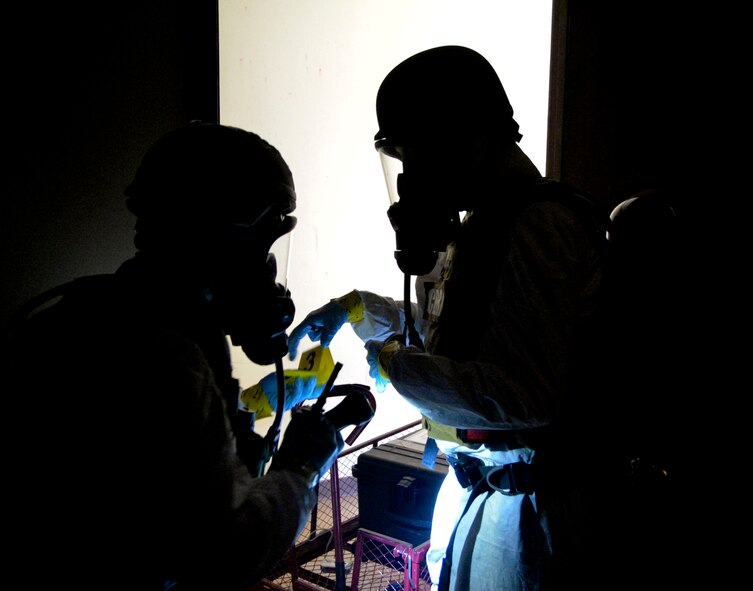 Staff Sgt. Elizabeth McCulley, 307th Bomb Wing emergency manager, and Airman 1st Class Victoria Hammond, 2nd Civil Engineer Squadron emergency manager specialist, sort out evidence collection cards on the ground on Barksdale Air Force Base, La., Oct. 29, 2014. Evidence Collection Cards are used to identify items that require further inspection and testing. (U.S. Air Force photo/Airman 1st Class Mozer O. Da Cunha)