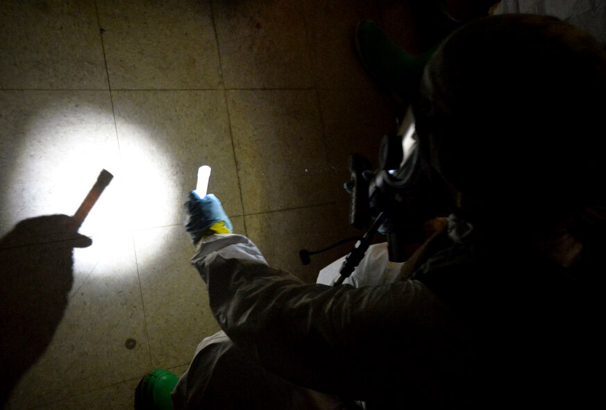Airman 1st Class Victoria Hammond, 2nd Civil Engineer Squadron emergency manager specialist, drops a glow stick on the floor on Barksdale Air Force Base, La., Oct. 29, 2014. Glow sticks are used to signal team members that a room has been inspected. Team members use different colors for inspected rooms and rooms that require further inspection. (U.S. Air Force photo/Airman 1st Class Mozer O. Da Cunha)
