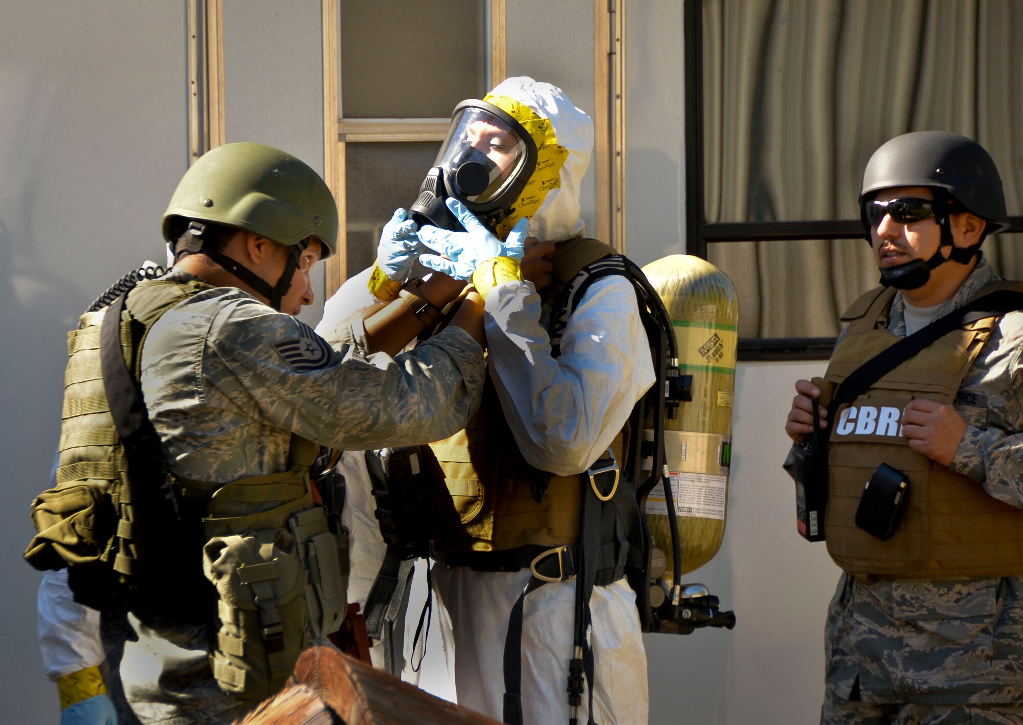 Tech. Sgt. Shawn Jamison, 2nd Civil Engineer Squadron installation emergency manager, assists Staff Sgt. Elizabeth McCulley, 307th Bomb Wing emergency manager, with a fire-hawk mask on Barksdale Air Force Base, La., Oct. 29, 2014. Fire-Hawk masks are used in environments where biological vapor hazards might be present. (U.S. Air Force photo/Airman 1st Class Mozer O. Da Cunha)