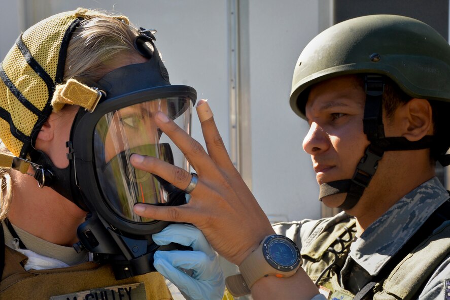 Tech. Sgt. Shawn Jamison, 2nd Civil Engineer Squadron installation emergency manager, assists Staff Sgt. Elizabeth McCulley, 307th Bomb Wing emergency manager, with a fire-hawk mask on Barksdale Air Force Base, La., Oct. 29, 2014. Fire-Hawk masks are used in environments where biological vapor hazards might be present. (U.S. Air Force photo/Airman 1st Class Mozer O. Da Cunha)