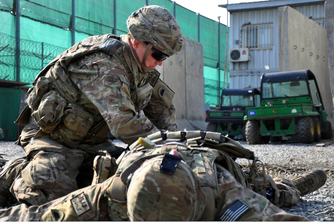 U.S. Army Spc. Evan P. Nelson assesses an injured soldier during a ...