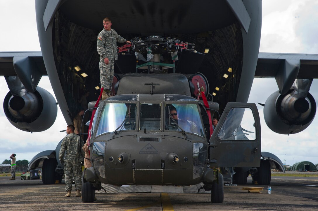 Service members unload a U.S. Army UH-60 Black Hawk from a U.S. Air Force C-17 Globemaster III Oct. 30, 2014, during Operation United Assistance. The U.S. Africa Command-led operation provides command and control, logistics, training and engineering support to the U.S. government’s efforts to contain the Ebola virus outbreak in West African nations. (U.S. Air Force photo/Staff Sgt. Gustavo Gonzalez)