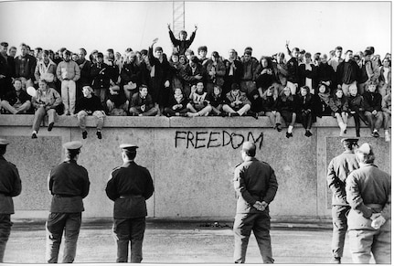 In November, 1989, East German students sit atop the Berlin Wall at the Brandenburg Gate in front of border guards. The destruction of the once-hated wall signaled the end of a divided Germany.

