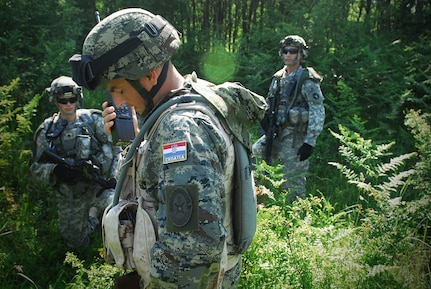 A Croatian joint-tactical air controller communicates with aircraft in the sky as Soldiers from B Company, 2nd Combined Arms Battalion., 136th Infantry, Minnesota National Guard, look on. B Company began honing and sharing skills and tactical knowledge with Croatian Army counterparts at an army base located in Slunj, a town in the mountains region of central Croatia. This Field Training Exercise (FTX) portion included exercises in cordon-and-search procedures, mounted and dismounted patrols and improvised explosive device (IED) clearance. Such training is a result of the State Partnership Program, which followed the dissolution of the Soviet Union.