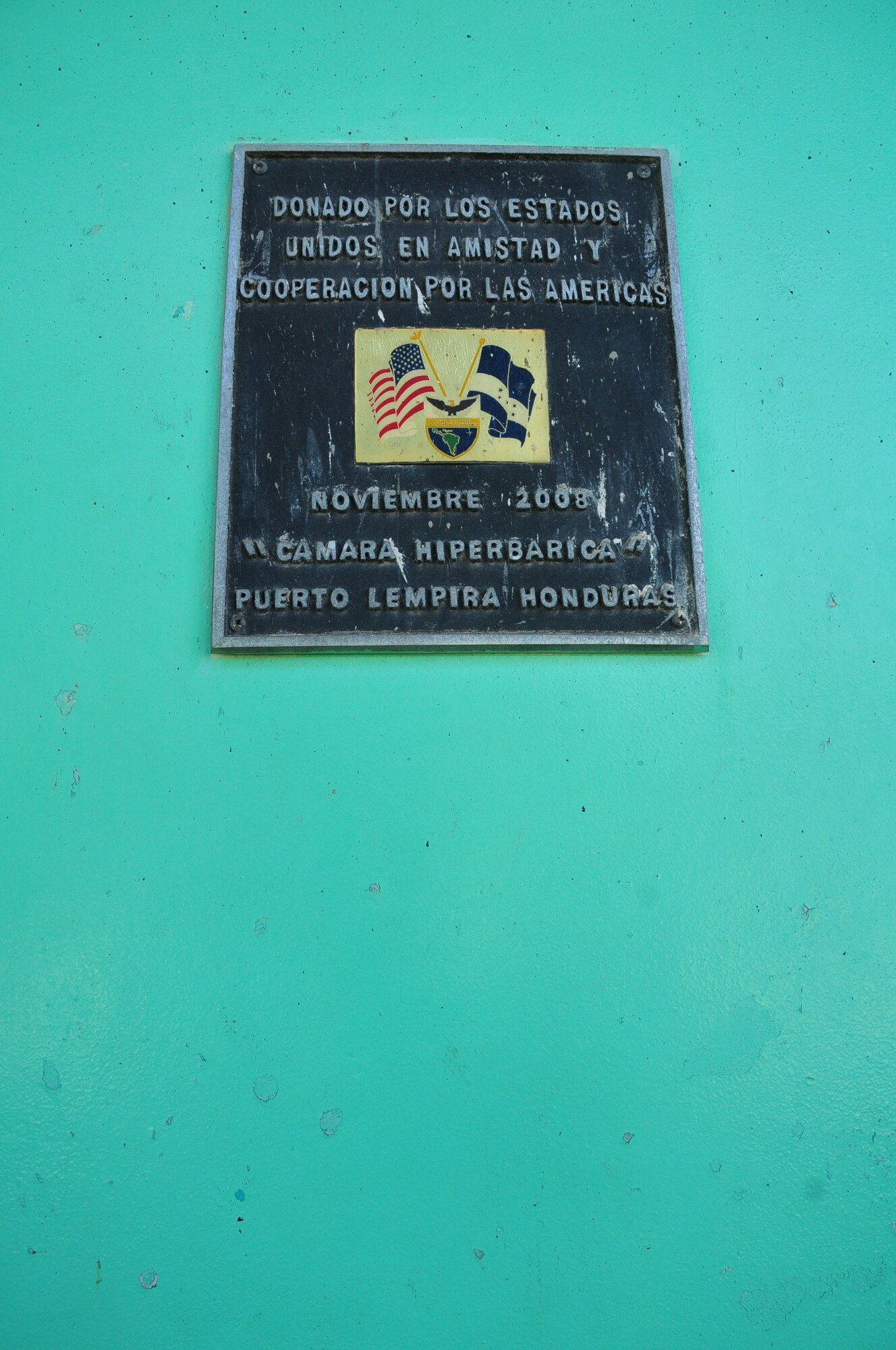 This plaque states that U.S. Southern Command donated a hyperbaric chamber to the Puerto Lempira hospital in 2008. The lobster industry is one of the main staples that support Puerto Lempira and the local area, and many divers who fish for the marine commodity have suffered from decompression sickness (DCS), also known as the bends. Exposure to DCS can produce many symptoms to include paralysis and death, but if treated early in a hyperbaric chamber, there is a significantly higher chance of successful recovery.  The donation was a critical aid to the Puerto Lempira region, and it emboldened SOUTHCOM's commitment to bring medical care and humanitarian assistance to Central America, further strengthening the partnership with the Hondurans. (U.S. Air Force Photo/ Capt. Connie Dillon)

