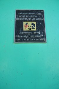 This plaque states that U.S. Southern Command donated a hyperbaric chamber to the Puerto Lempira hospital in 2008. The lobster industry is one of the main staples that support Puerto Lempira and the local area, and many divers who fish for the marine commodity have suffered from decompression sickness (DCS), also known as the bends. Exposure to DCS can produce many symptoms to include paralysis and death, but if treated early in a hyperbaric chamber, there is a significantly higher chance of successful recovery.  The donation was a critical aid to the Puerto Lempira region, and it emboldened SOUTHCOM's commitment to bring medical care and humanitarian assistance to Central America, further strengthening the partnership with the Hondurans. (U.S. Air Force Photo/ Capt. Connie Dillon)

