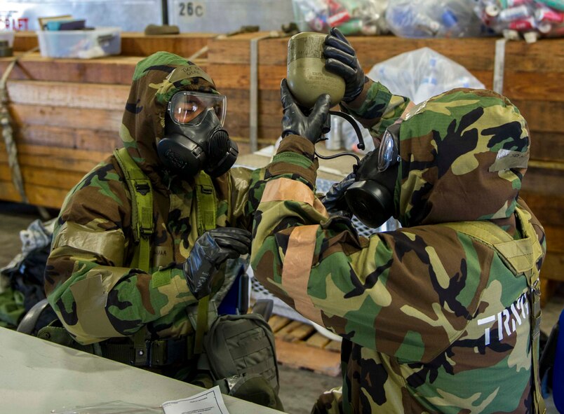 Tech. Sgt. Ty Tanaka, left, and Tech. Sgt. Jim Willard, both 154th Aircraft Maintenance Squadron C-17 Globemaster III specialists, practice drinking water from a canteen while in mission oriented protective posture 4 during a chemical, biological, radiological, nuclear and  high-yield explosive exercise on Joint Base Pearl Harbor-Hickam, Hawaii, Nov. 7, 2014. Throughout the exercise, Airmen were tested on their ability to continue their mission after donning MOPP gear, conduct post attack reconnaissance sweeps, react to alarm signals, decontaminate equipment and administer self-aid and buddy care. (U.S. Air Force photo by Tech. Sgt. Terri Paden)