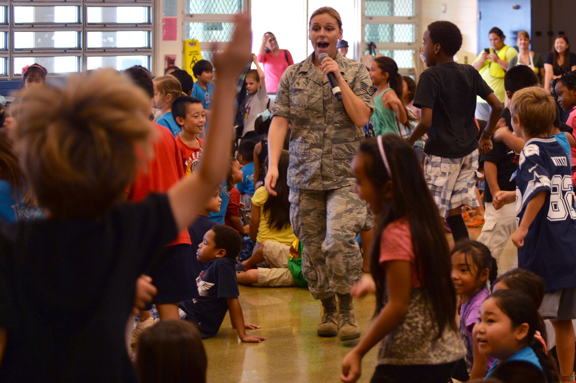 Staff Sgt. Courtney Clifford, a vocalist with the U.S. Air Force Band of the Pacific-Hawaii, walks through an excited audience during a performance for Kapolei Elementary School students and faculty members in Kapolei, Hawaii, Nov. 5, 2014. The performance was part of the school’s observance of National Red Ribbon Week that raises awareness of the effects of drug use. (U.S. Air Force photo by Staff Sgt. Alexander Martinez)  
