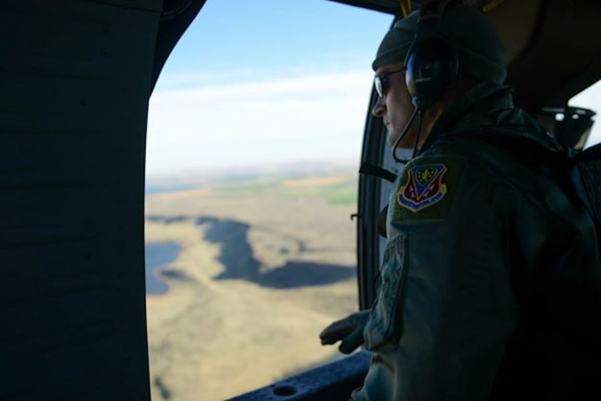Capt. James Wirthlin, 391st Fighter Squadron flight surgeon, looks out a UH-60 Blackhawk over Saylor Creek Range, Idaho, Nov. 6, 2014. Wirthlin flew with a retrieval team to observe medical evacuation training. (U.S. Air Force photo by Airman 1st Class Jessica H. Smith/RELEASED)