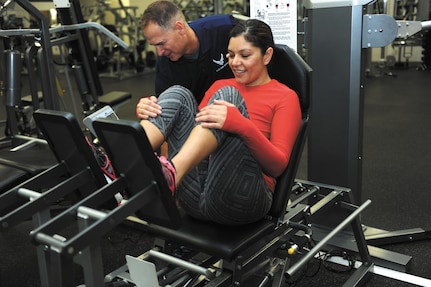 Gateway Fitness Center trainer Mike White sets Tech Sgt. Rebeca Mendoza’s resistance levels for leg press training Nov. 6 at the Gateway Fitness Center. Mendoza, 433rd Medical Squadron education and training manager, is training to compete in the San Antonio Rock ‘n’ Roll Half-Marathon Dec. 7 (photo by Staff Sgt. Marissa Garner).