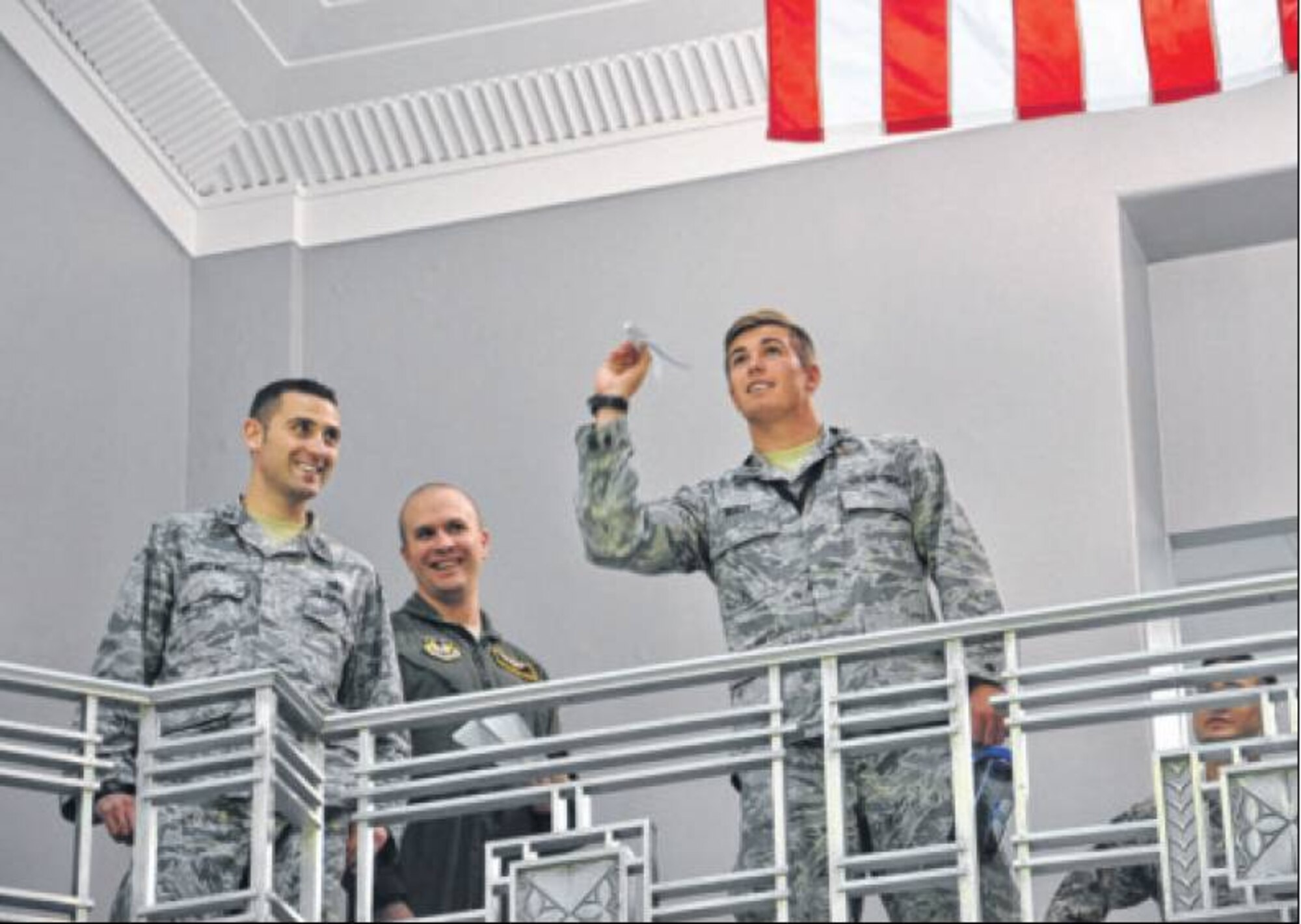 (From left) Capt. Daniel Luczak of the Air Force Life Cycle Management Center (AFLCMC) and Master Sgt. Matthew Weede of Air Force Materiel Command look on as 2nd Lt. Max Reilly of AFLCMC prepares to launch his paper airplane during a fundraiser for the Miami Valley Combined Federal Campaign on Oct. 29 in the rotunda of Bldg. 12, home of AFLCMC’s Agile Combat Support Directorate, the contest’s sponsor. (Air Force photos by Diane Kofoed)