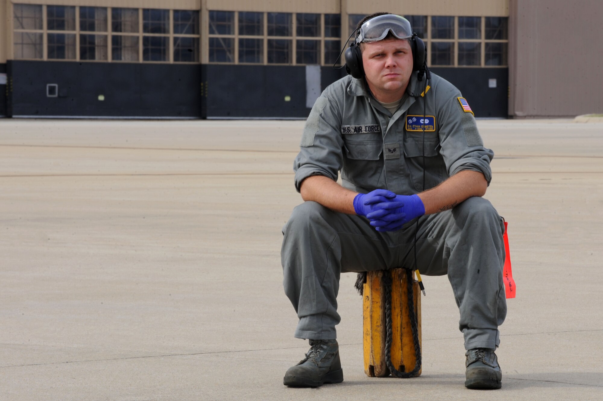 U.S. Air Force Senior Airman Ethan Edmisten, 20th Aircraft Maintenance Squadron dedicated crew chief, sits on a pair of wheel chocks during hot pit refueling at Shaw Air Force Base, S.C., Nov. 5, 2014. Edmisten ,along with other Airmen assigned to the 20th AMXS, practiced hot pit refueling, a technique used to rapidly refuel aircraft in a combat situation. (U.S. Air Force photo by Airman 1st Class Michael Cossaboom/Released)