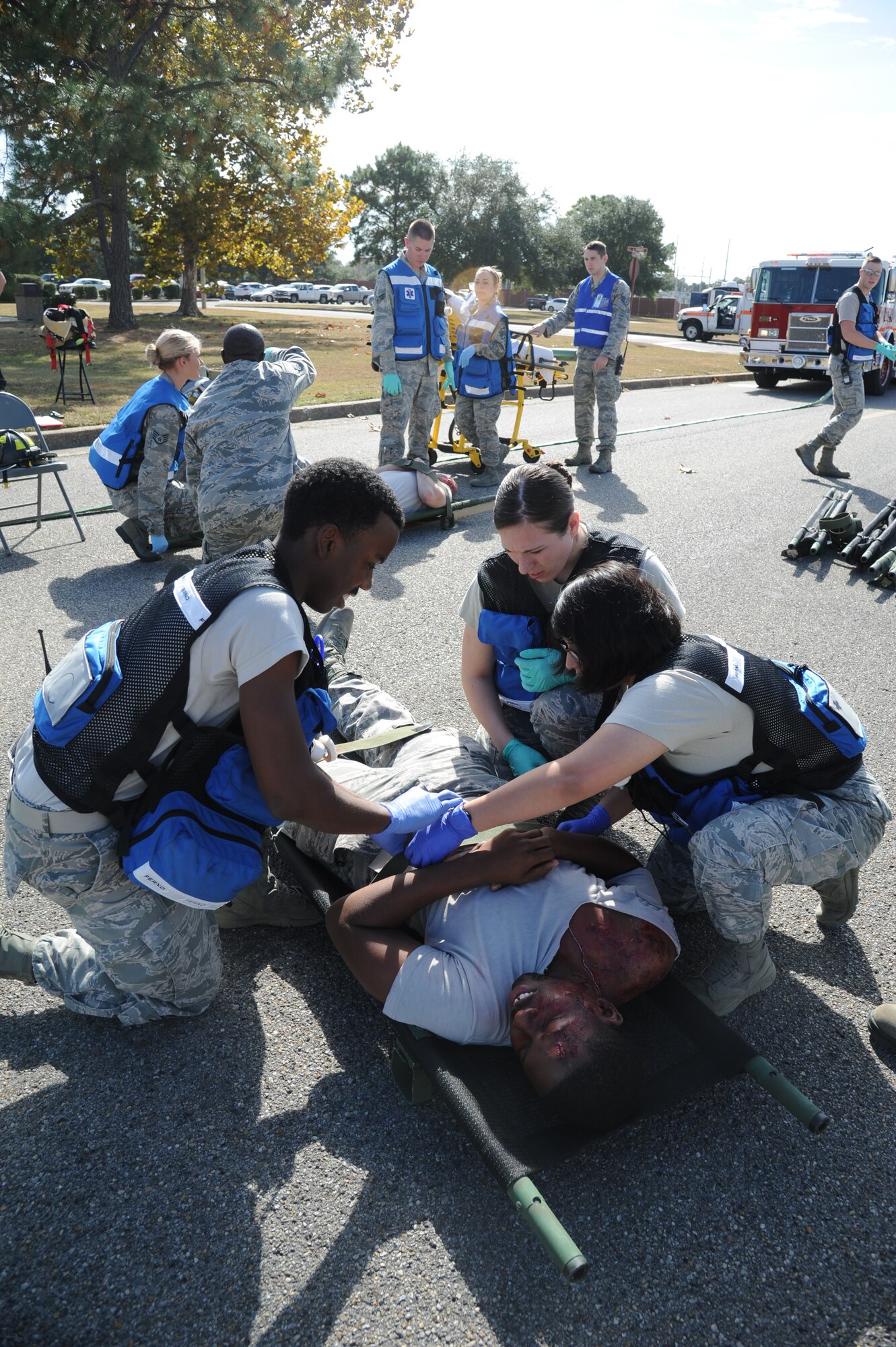 Airman 1st Class Corey Owens, Senior Airman Kayla Sloan and Airman 1st Class Claudia Godinez, 81st Aerospace Medicine Squadron flight medicine technicians and field response team members, secure Airman 1st Class Miles Walker, 81st Force Support Squadron, to a litter as he portrays an injured “victim” during a hazardous material exercise scenario Nov. 5, 2014, at the Taylor Logistics Center, Keesler Air Force Base, Miss The exercise scenario began with an Airman accidentally hitting a 55-gallon drum of sulfuric acid with a forklift and knocking several more drums off of a truck causing the liquid to splash onto other Airmen.  Immediately, the Airmen simulated skin and eye burns from exposure to the agent, while additional Airmen on the loading dock started coughing and experiencing shortness of breath. (U.S. Air Force photo by Kemberly Groue)