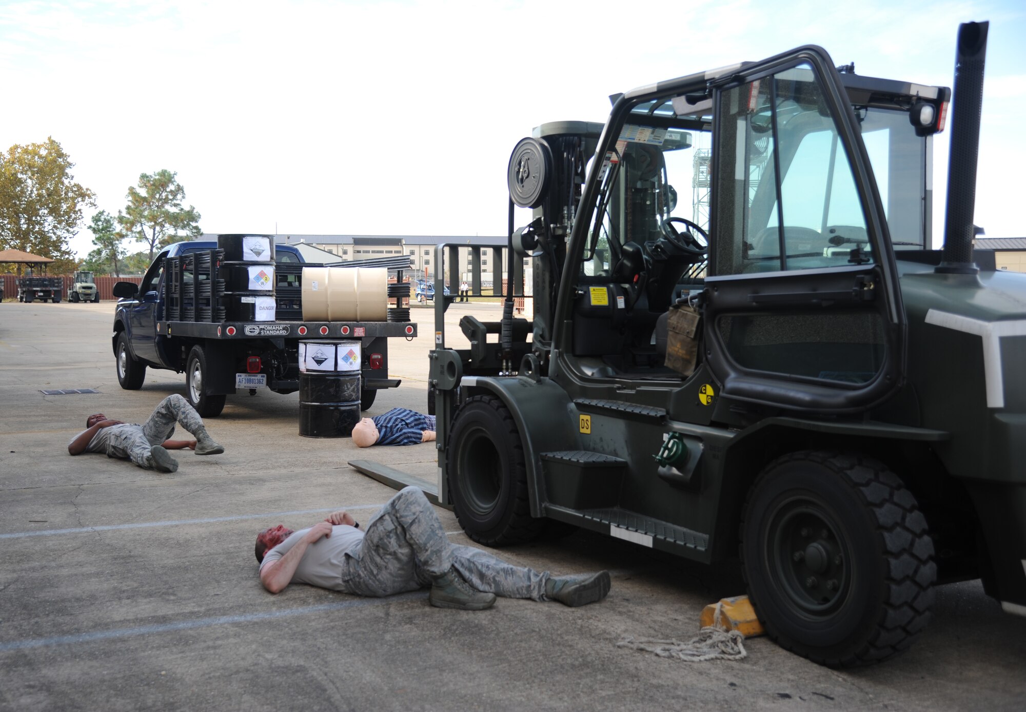 Airman 1st Class Miles Walker, 81st Force Support Squadron, and Senior Airman Willie Moore, 81st Logistics Readiness Squadron forklift operator, portray injured “victims” during a hazardous material exercise scenario Nov. 5, 2014, at the Taylor Logistics Center, Keesler Air Force Base, Miss.  The exercise scenario began with an Airman accidentally hitting a 55-gallon drum of sulfuric acid with a forklift and knocking several more drums off of a truck causing the liquid to splash onto other Airmen.  Immediately, the Airmen simulated skin and eye burns from exposure to the agent, while additional Airmen on the loading dock started coughing and experiencing shortness of breath. Moore was the simulated driver of the forklift. (U.S. Air Force photo by Kemberly Groue)
