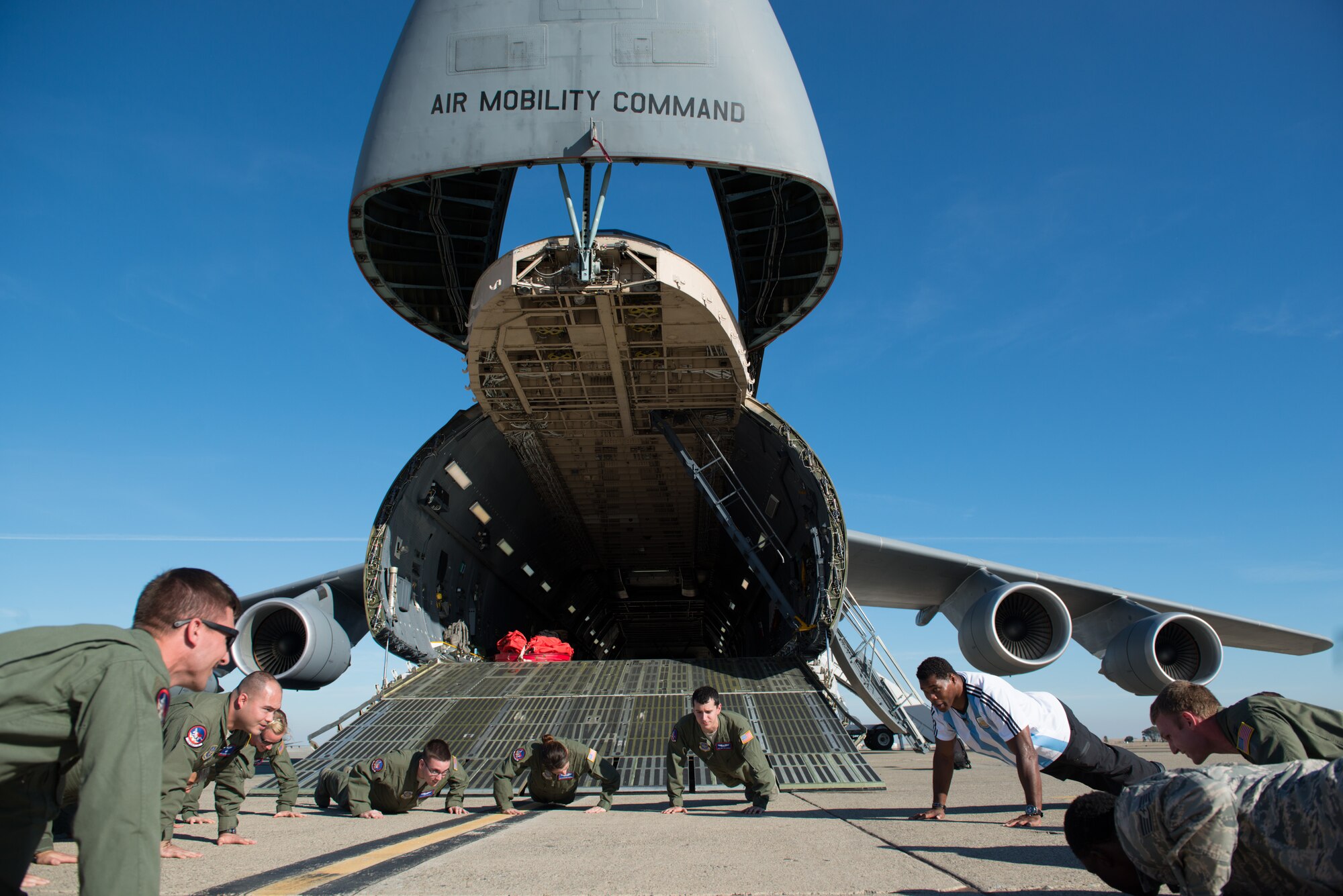 Herschel Walker, former NFL running back and Heisman Trophy winner, challenged C-5M Super Galaxy aircrew members to multiple sets of push-ups Wednesday in front of their aircraft. Walker met with Airmen at Travis to share his personal story and experience with seeking help for mental illness. (U.S. Air Force photo by Ken Wright)