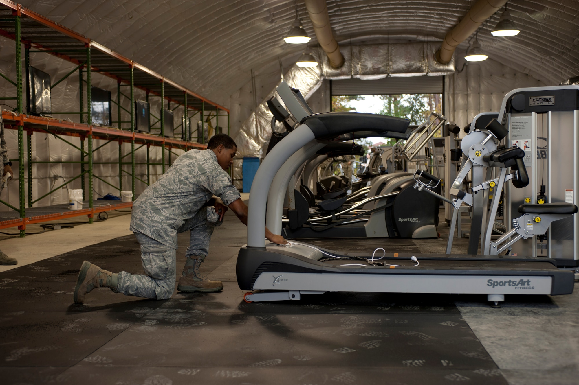 Senior Airman David Royal, 633rd Force Support Squadron fitness assessment cell monitor, cleans equipment transferred from base fitness centers to the Langley Transit Center at Langley Air Force Base, Va., Nov. 6, 2014. The Secretary of Defense signed into action a 21-day controlled monitoring period for all returning Service members from West Africa, and Joint Base Langley-Eustis is designated as one of Department of Defense’s controlled monitoring sites. Within four days, members assigned to the 633rd Air Base Wing setup hard-stand billets, an expeditionary dining facility, a contingency fitness center, morale welfare and recreation facilities, high-speed Internet access and cable television to accommodate Service members staying at the center.  (U.S. Air Force photo by Staff Sgt. Natasha Stannard/Released)