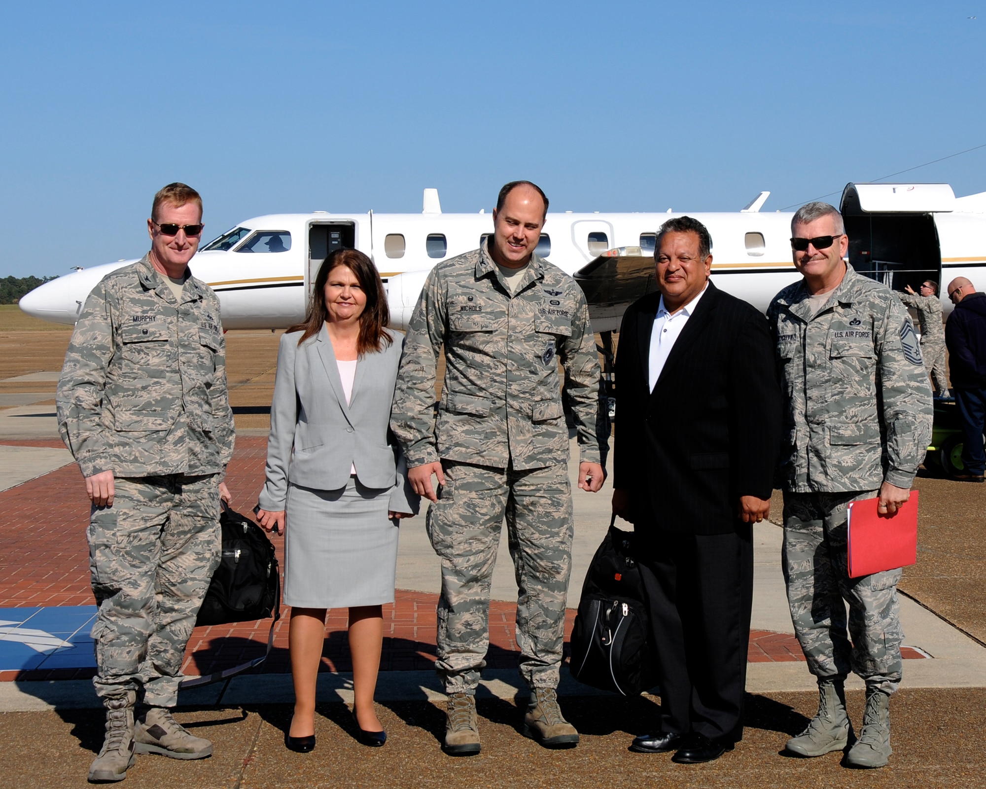 Col. John Murphy, Air Education and Training Command Deputy Directory of Logistics, Installations and Mission Support, left; SES 2 Gilbert Montoya, AETC Directory of Logistics, Installations and Mission Support, second from right; and Chief Master Sgt.  Eric Honeycutt, AETC Civil Engineer Functional Manager, right, are greeted on the Columbus Air Force Base flightline “red carpet” Nov. 3 by Col. John Nichols, 14th Flying Training Wing Commander, center, and Edna Crossman, 14th FTW Chief of Protocol, second from left, upon the group’s arrival for a two-day base visit. The AETC A4/7 Team began their visit meeting senior wing leaders and receiving a 14th Flying Training Wing mission briefing describing the landscape of the past, present and future of Columbus AFB.  (US Air Force Photo/Sharon Ybarra)