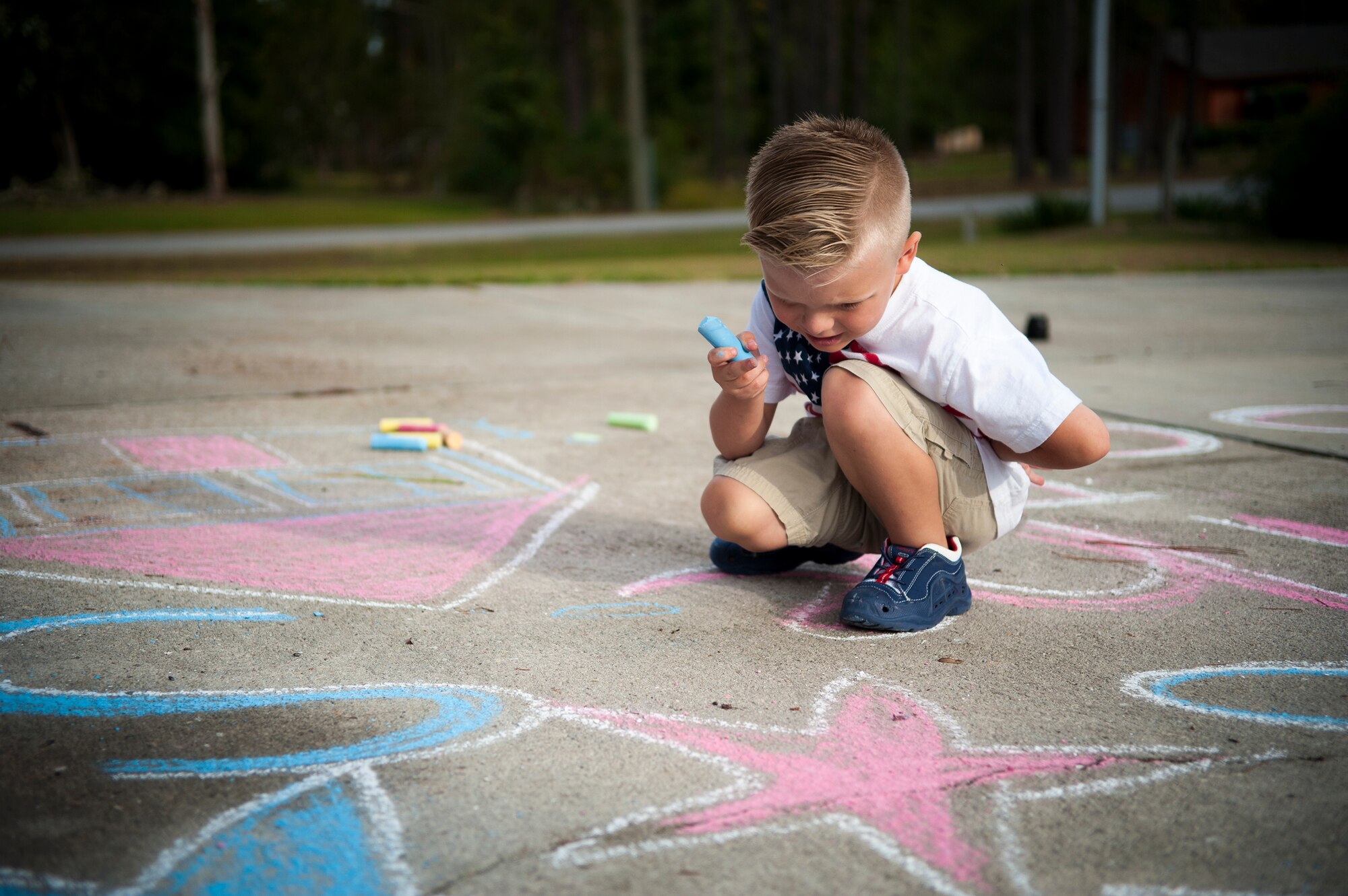 Silas Lanthorn, son of U.S. Air Force Staff Sgt. Lee Lanthorn, pauses before finishing a chalk drawing at their home in Valdosta, Ga., Nov. 5, 2014. Three-year-old Silas helped his mom Shelley decorate their driveway in preparation for his father’s return from a six month deployment.  (U.S. Air Force photo by Andrea Jenkins/Released)