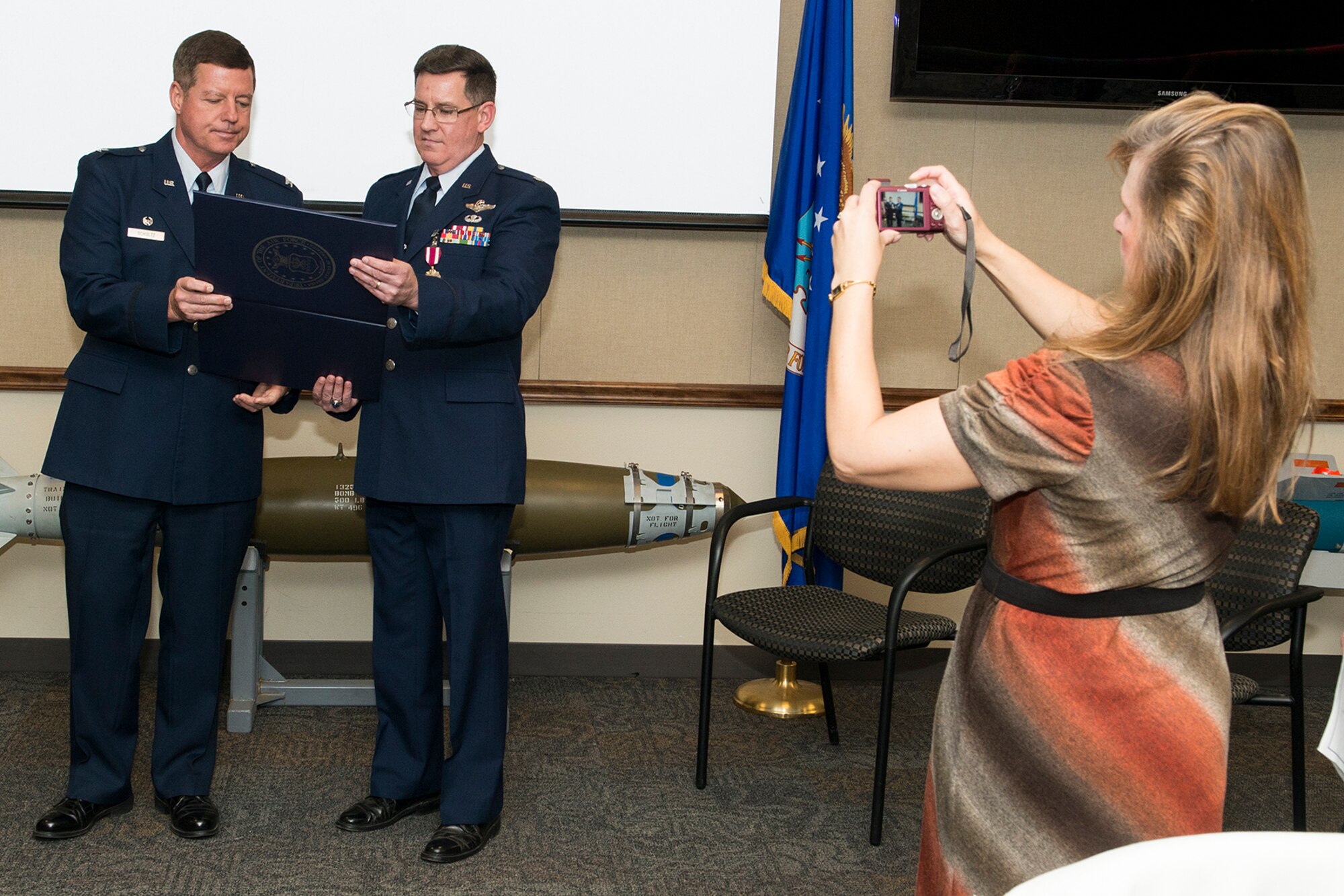 Debbie Polomoscanik takes of photo of your husband, Lt. Col. Ronald Polomoscanik (right), as he reads his retirement certificate during a ceremony on Nov. 2, 2014, Barksdale Air Force Base, La. Polomoscanik is the Director of Operations for the 343rd Bomb Squadron and is retiring from the Air Force Reserve. (U.S. Air Force photo by Master Sgt. Greg Steele/Released)