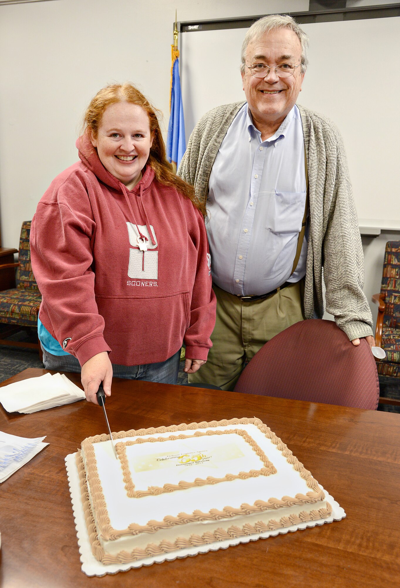 DLA Document Services celebrated its 65th anniversary on Monday by having the acting director of the Tinker branch, Mike Smith, and the youngest member of the Tinker staff, Amanda Blanchard, cut the cake. Headquarters Director Steve Sherman gave a history of their organization through a teleconference call, citing important dates, such as how the organization was created in 1949 and became the Department of Defense Printing Service. In October of 1996, they became a part of DLA, and in 2010 were renamed DLA Document Services. Their mission is to prints various maps, manuals and orders to directly serve the warfighter. (Air Force photo by Kelly White)