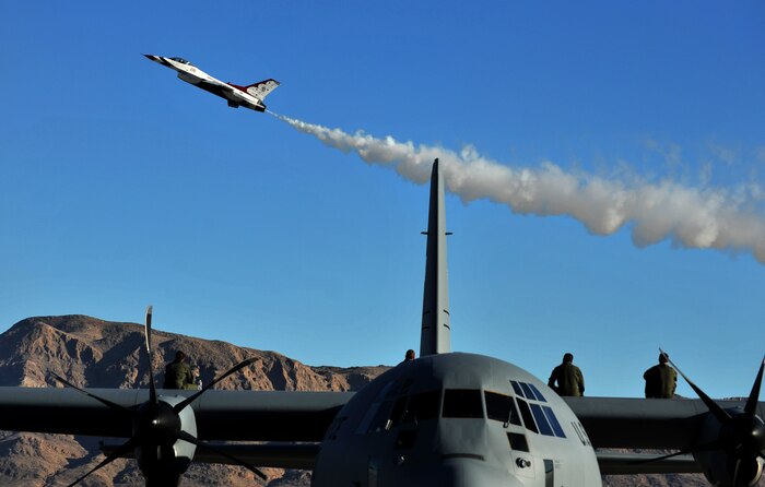 The aircrew of a C-130J Hercules sit atop the aircraft to watch the practice performance of the U.S. Air Force Aerial Demonstration Team, or Thunderbirds, Nov. 7, 2014, at Nellis Air Force Base, Nev. Several military aerial demonstration teams, including the U.S. Air Force Aerial Demonstration Squadron, the Thunderbirds, will participate. The open house also acts as the final air show of the year for the Thunderbirds. (U.S. Air Force photo by Senior Master Sgt. Cecilio Ricardo)