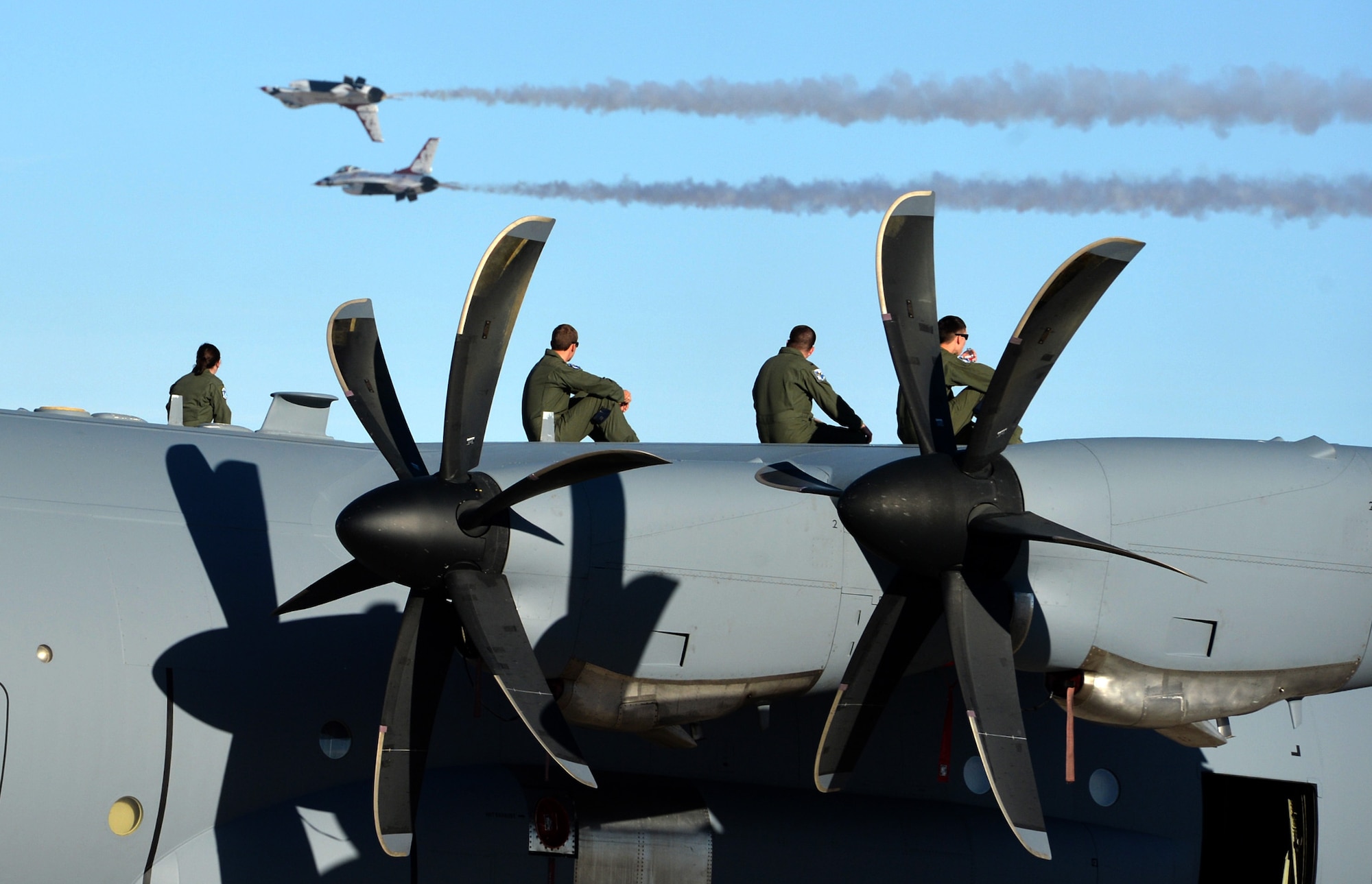 The aircrew of a C-130J Hercules sit atop the aircraft to watch the practice performance of the U.S. Air Force Aerial Demonstration Team, or Thunderbirds, Nov. 7, 2014, at Nellis Air Force Base, Nev. Several military aerial demonstration teams, including the U.S. Air Force Aerial Demonstration Squadron, the Thunderbirds, will participate. The open house also acts as the final air show of the year for the Thunderbirds. (U.S. Air Force photo by Tech. Sgt. Nadine Barclay)