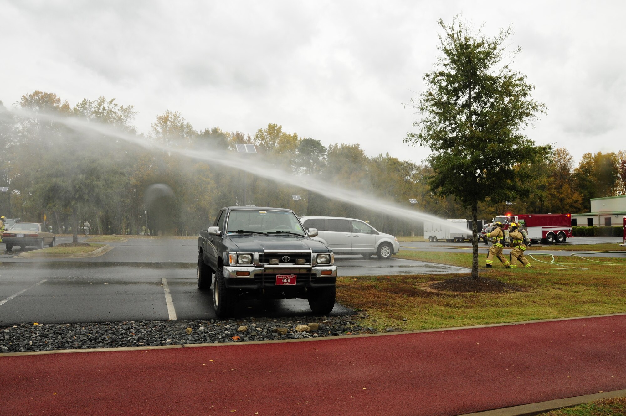 U.S. Air Force Staff SSgt’s Brian Campbell and Joseph Upchurch, firefighters for the 145th Civil Engineer Squadron, use a high pressure fire hose to simulate putting out a fire during the 145th Airlift Wing’s annual Anti-Terrorism Exercise simulating a car bomb detonation inside the perimeter of the North Carolina Air National Guard Base, Charlotte Douglas Intl. Airport, Nov. 1, 2014. The exercise initiated force protection measures across the base and tested the Wing’s ability to respond accordingly. (U.S. Air National Guard photo by Senior Airman Laura J. Montgomery, 145th Public Affairs/Released)