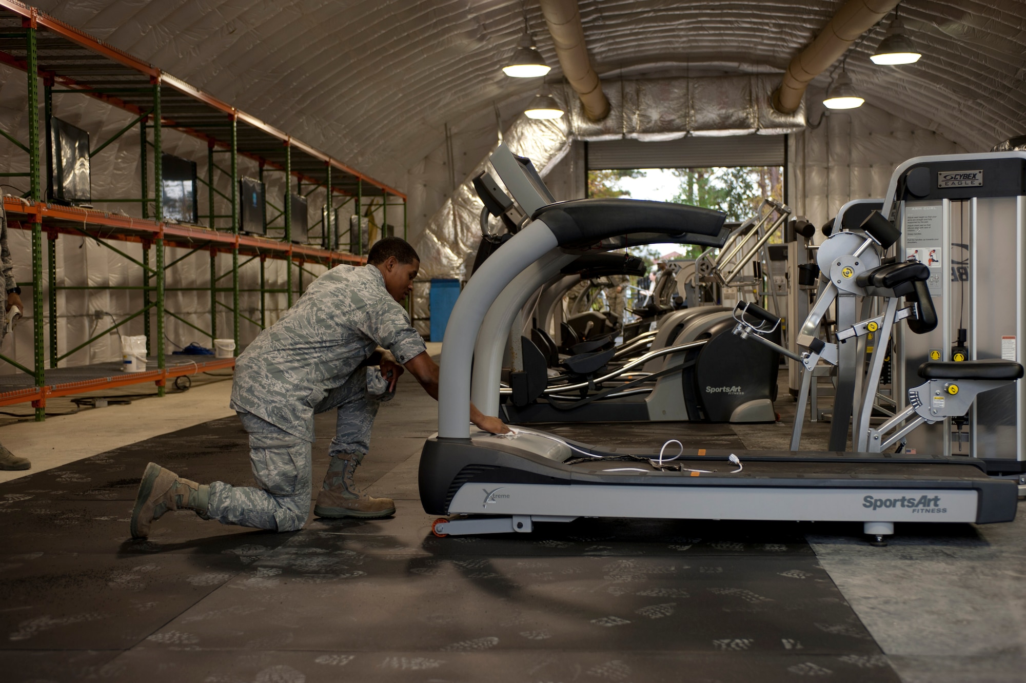 Senior Airman David Royal cleans equipment transferred from base fitness centers Nov. 6, 2014, to the Langley Transit Center at Langley Air Force Base, Va. The Secretary of Defense signed into action a 21-day controlled monitoring period for all returning service members from West Africa, and Joint Base Langley-Eustis is designated as one of Department of Defense’s controlled monitoring sites. Within four days, members assigned to the 633rd Air Base Wing set up an expeditionary dining facility, a contingency fitness center, morale welfare and recreation facilities, high-speed internet access and cable television to accommodate service members staying at the center. Royal is a 633rd Force Support Squadron fitness assessment cell monitor. (U.S. Air Force photo/Staff Sgt. Natasha Stannard)