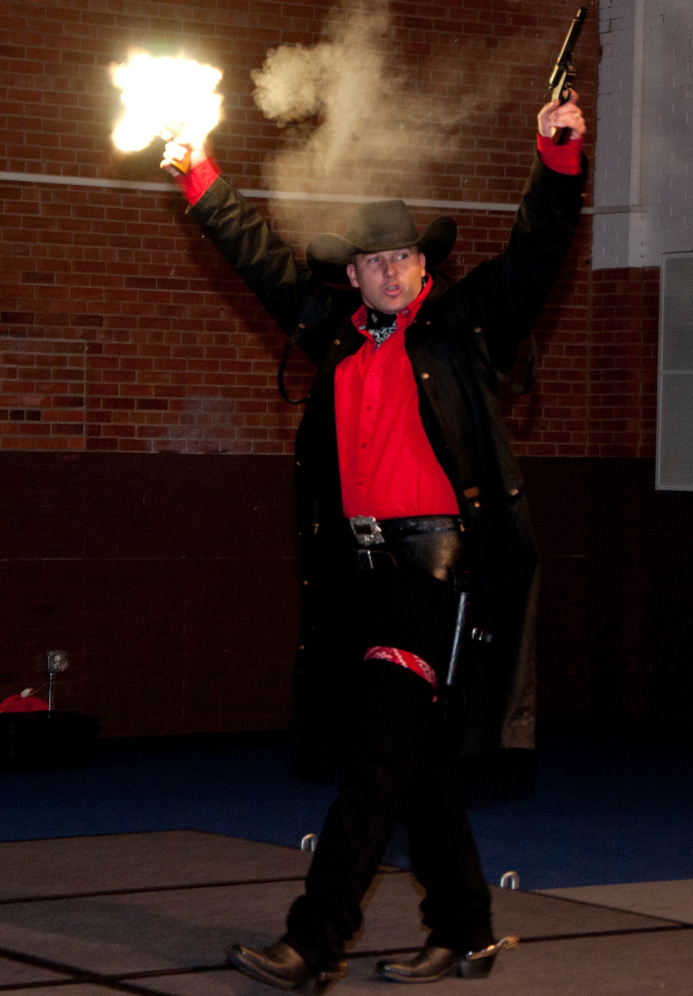 The Warren Wrangler, the 90th Missile Wing's official Global Strike Challenge mascot, portrayed this year by 1st Lt. Joshua Haynes, 90th Operations Support Squadron senior crew instructor, steps on the stage, guns blazing, in the Fall Hall Community Center on F.E. Warren Air Force Base, Wyo., Nov. 7, 2014, during the Mighty Ninety's GSC homecoming. The Wrangler rallied the crowd to cheer on the competitors as they were introduced. (U.S. Air Force photo by Senior Airman Jason Wiese)